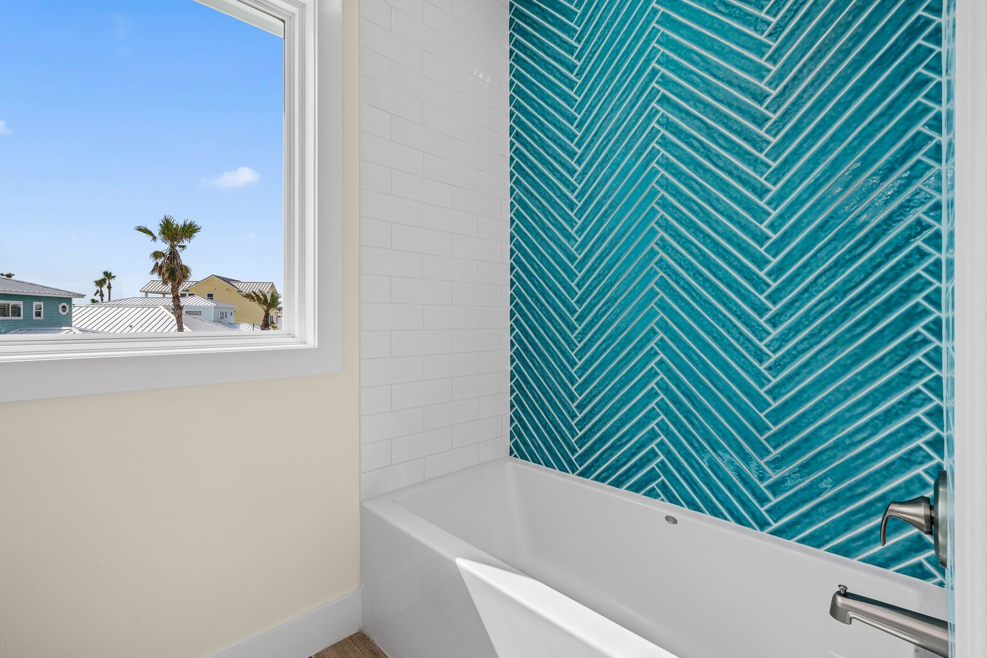 A bathroom with a tub and a window with a view of the ocean.