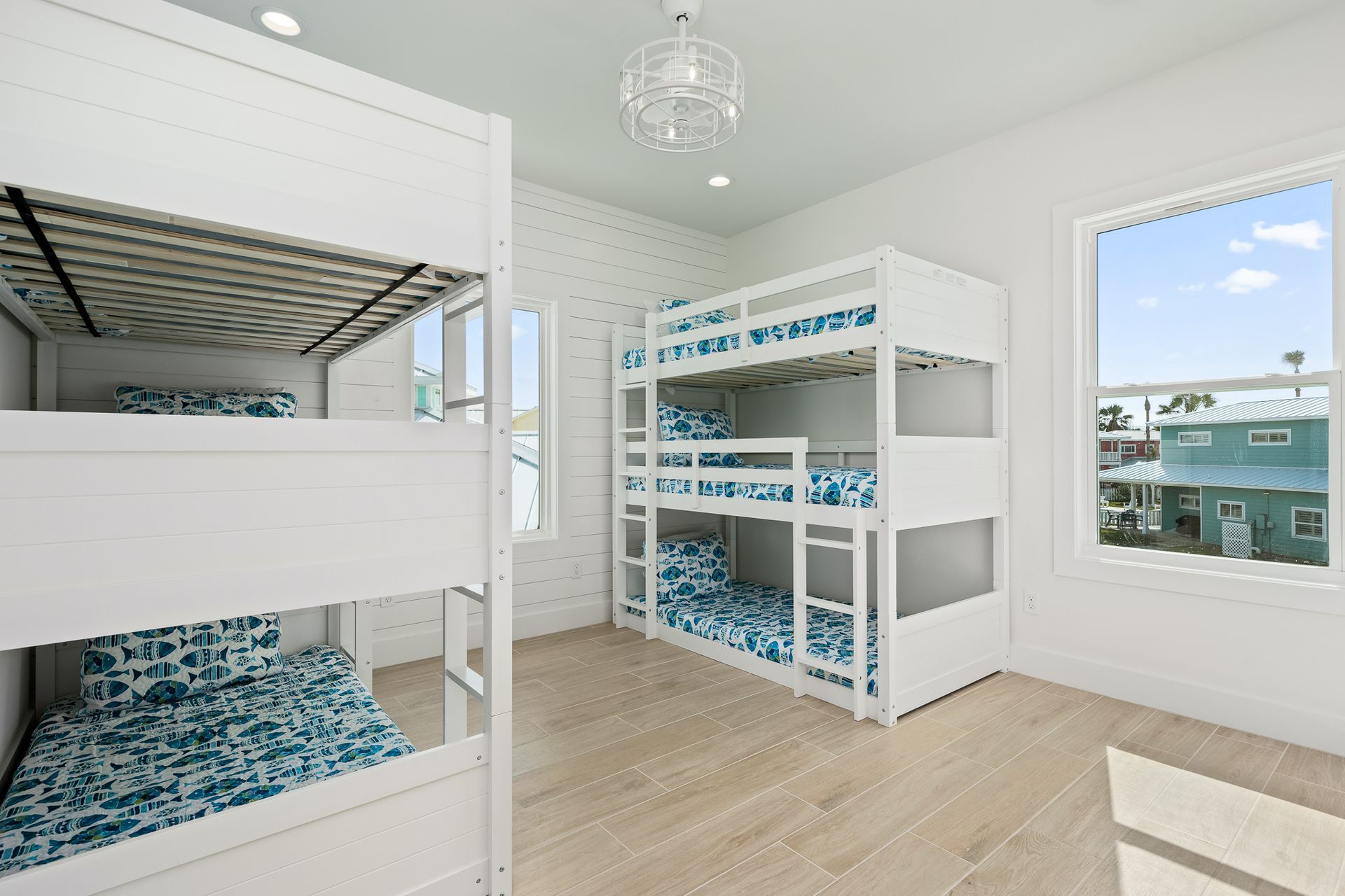 A bedroom with three bunk beds and two windows.