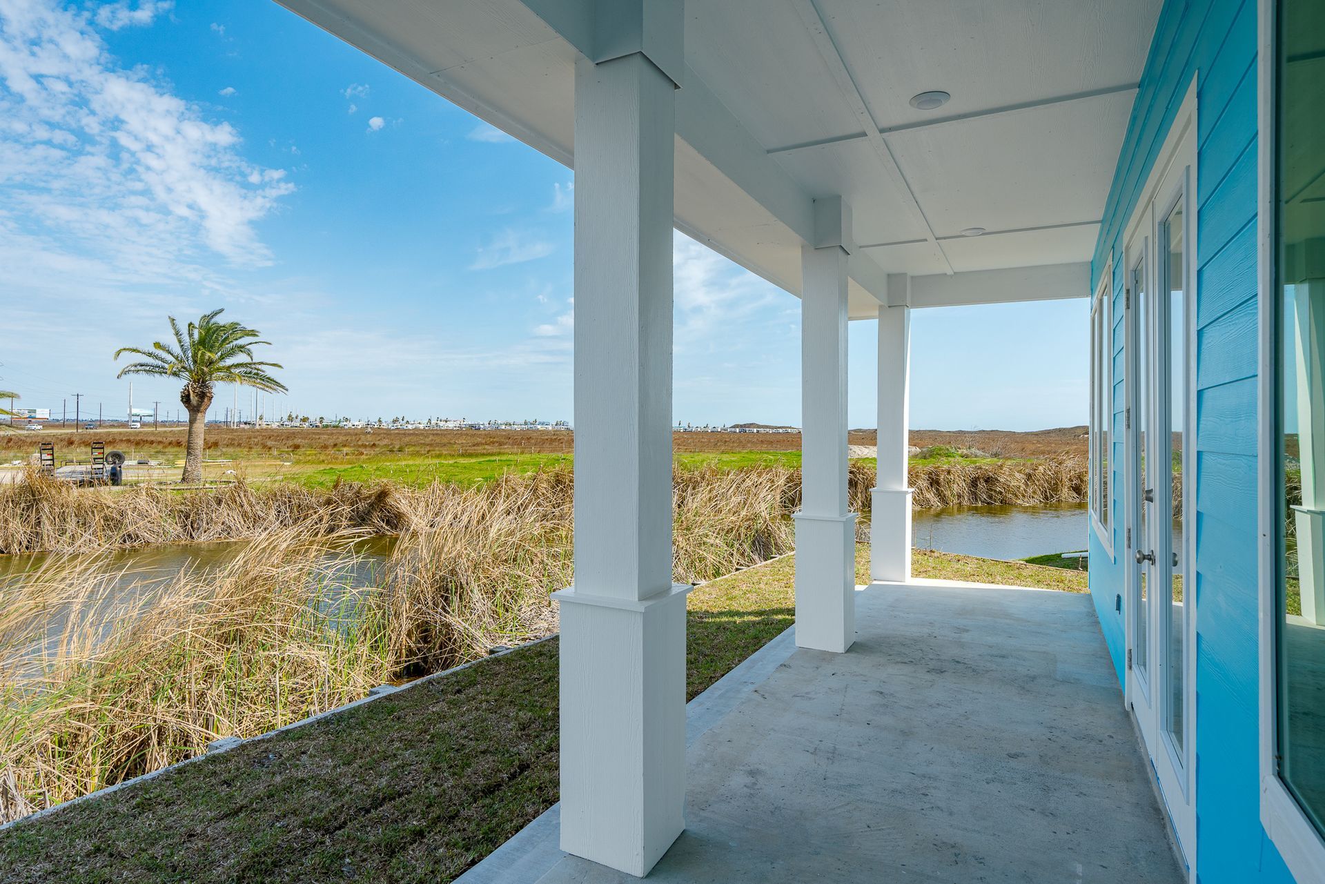 A blue house with a porch overlooking a body of water.