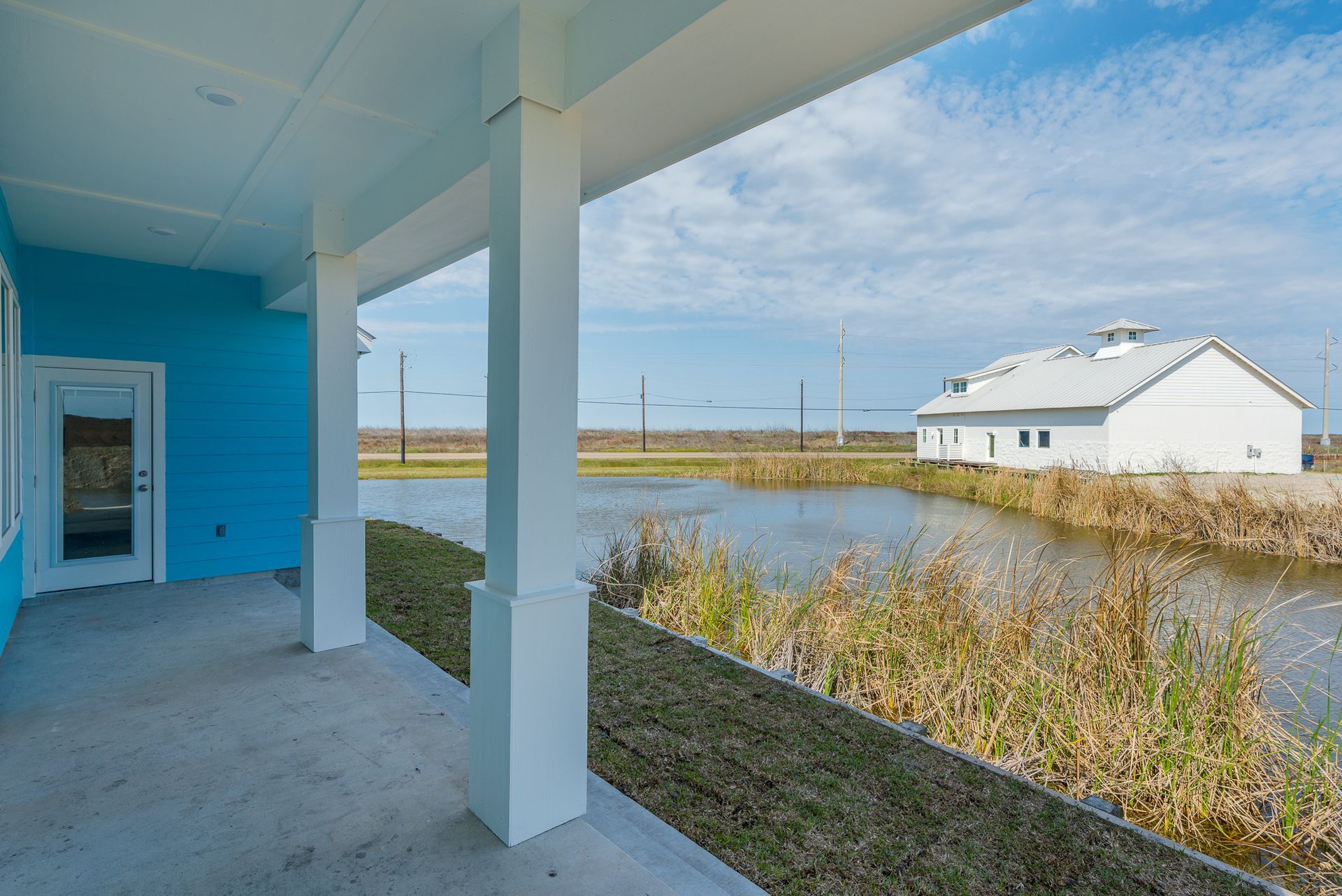 A blue house with a porch overlooking a body of water.