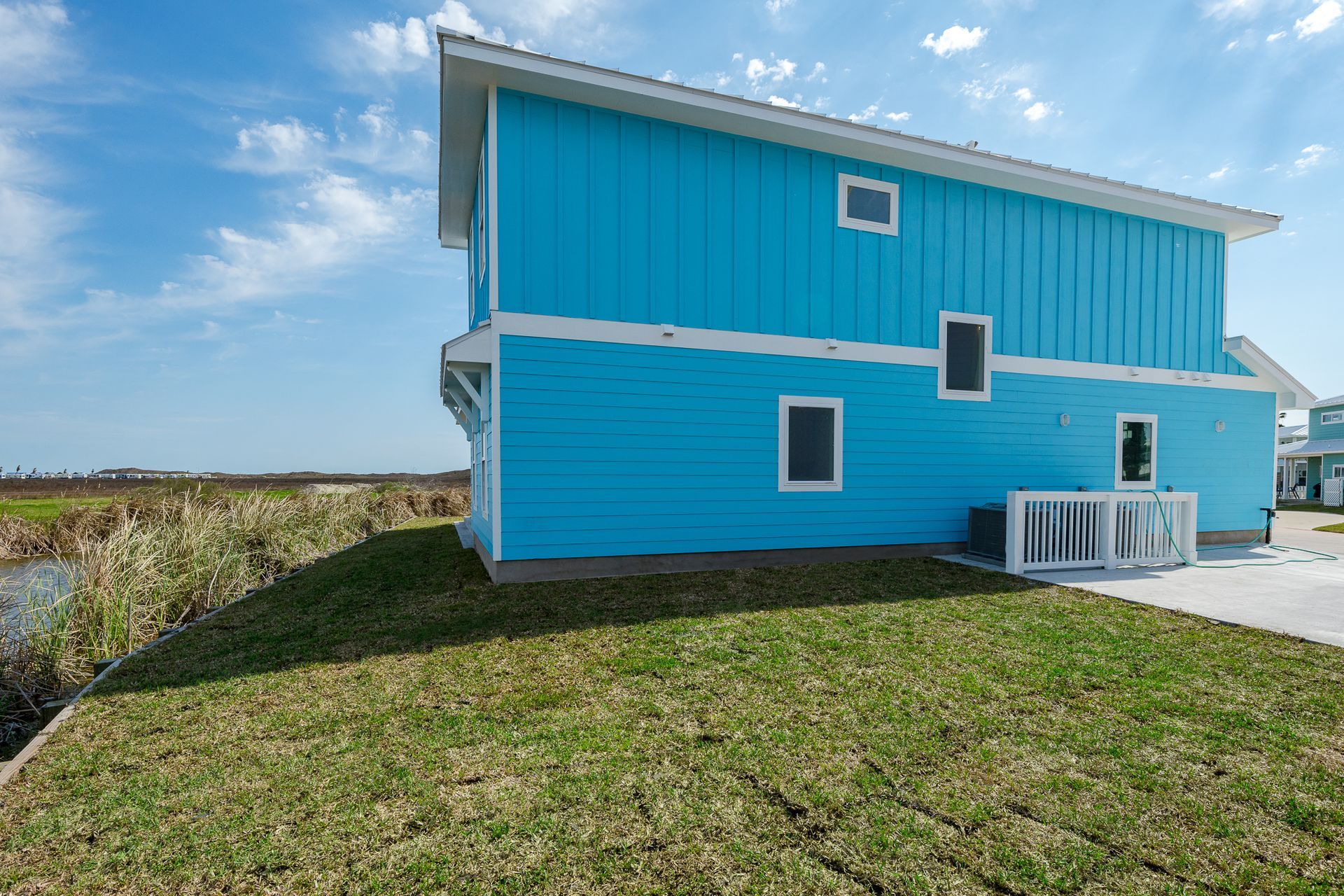 A blue and white house is sitting on top of a lush green field.