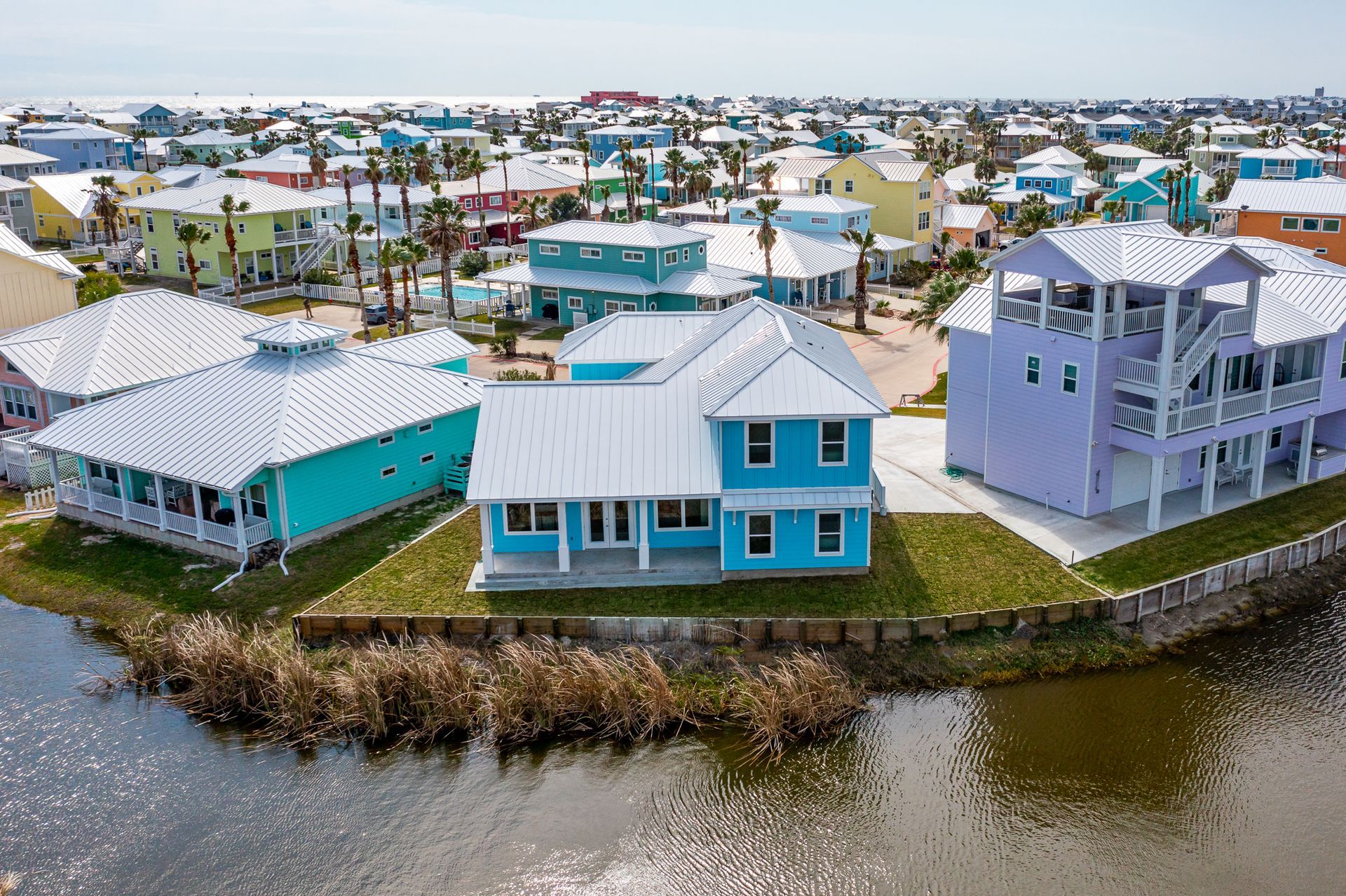 A group of colorful houses are sitting on a small island in the middle of a body of water.