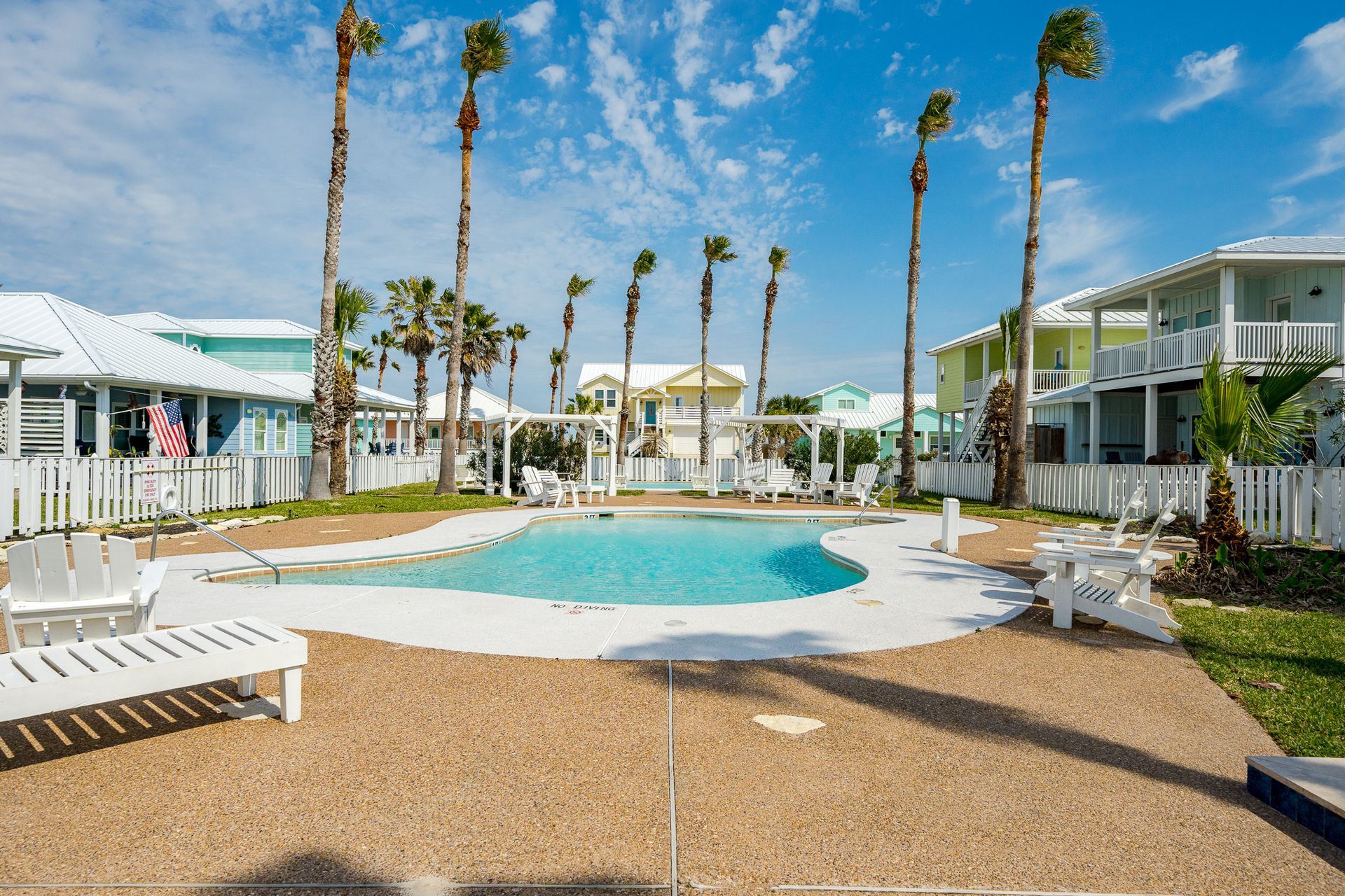 A large swimming pool surrounded by palm trees in a resort.