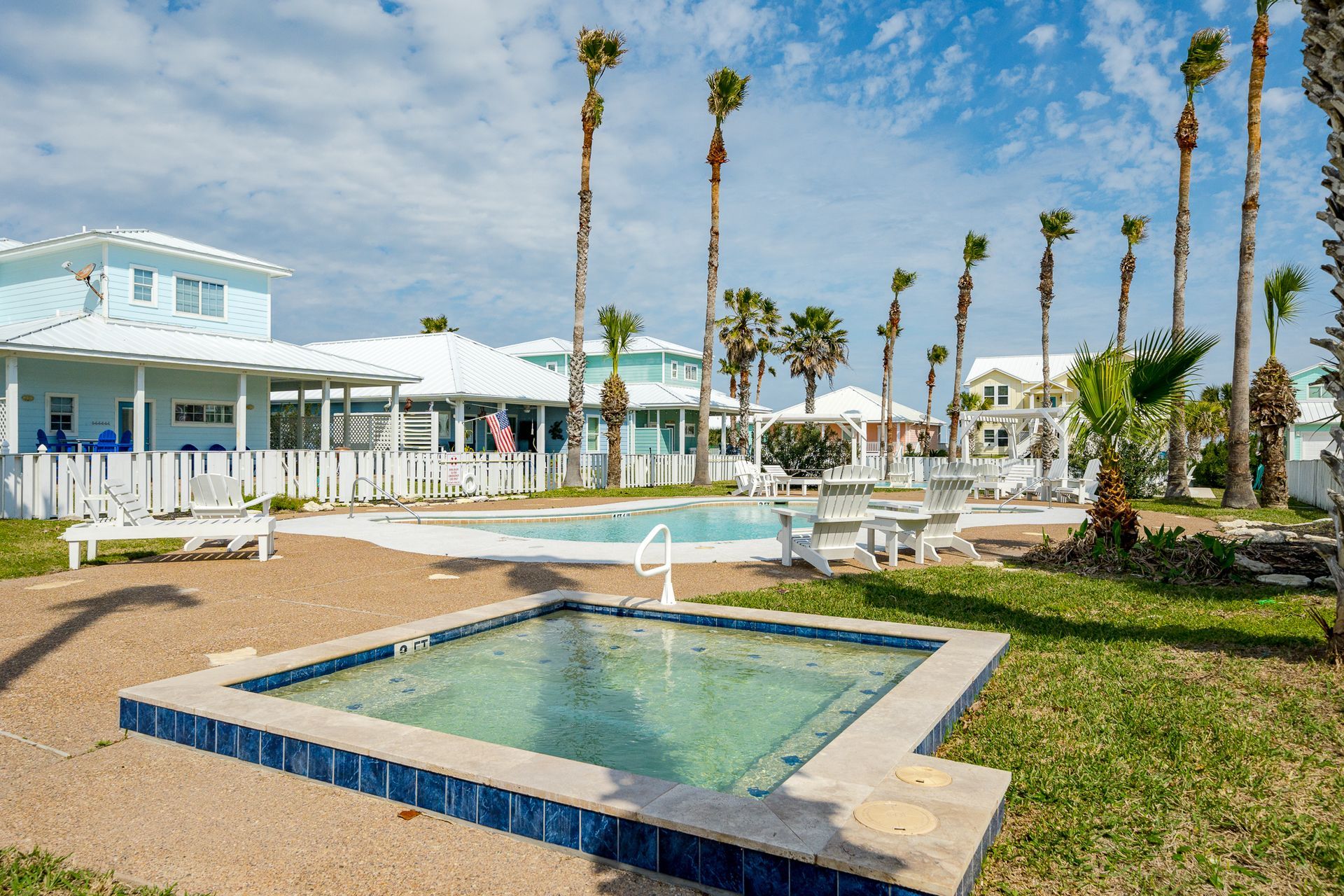 A swimming pool with a hot tub in the middle of it in front of a house.