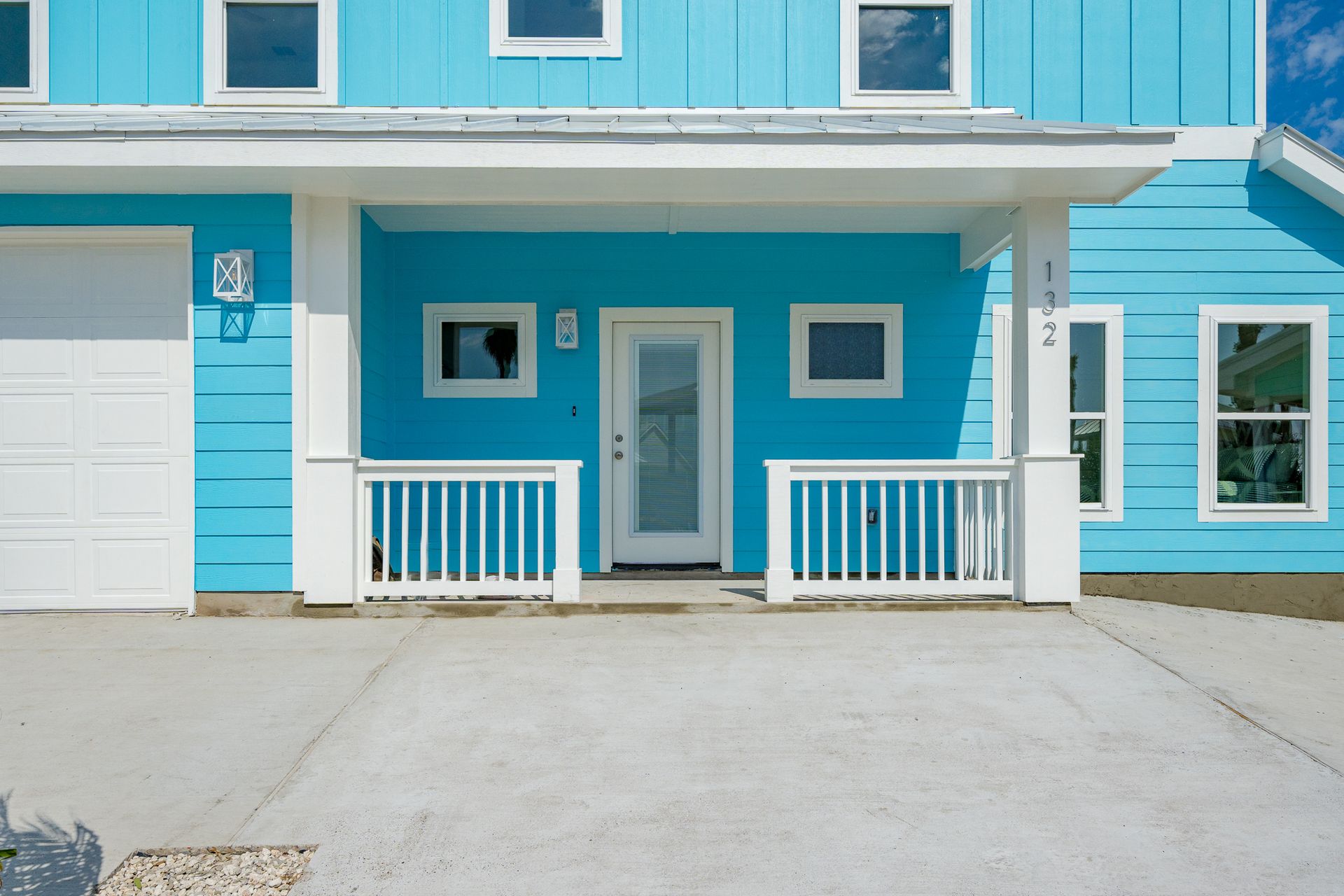 A blue house with white trim and a white garage door