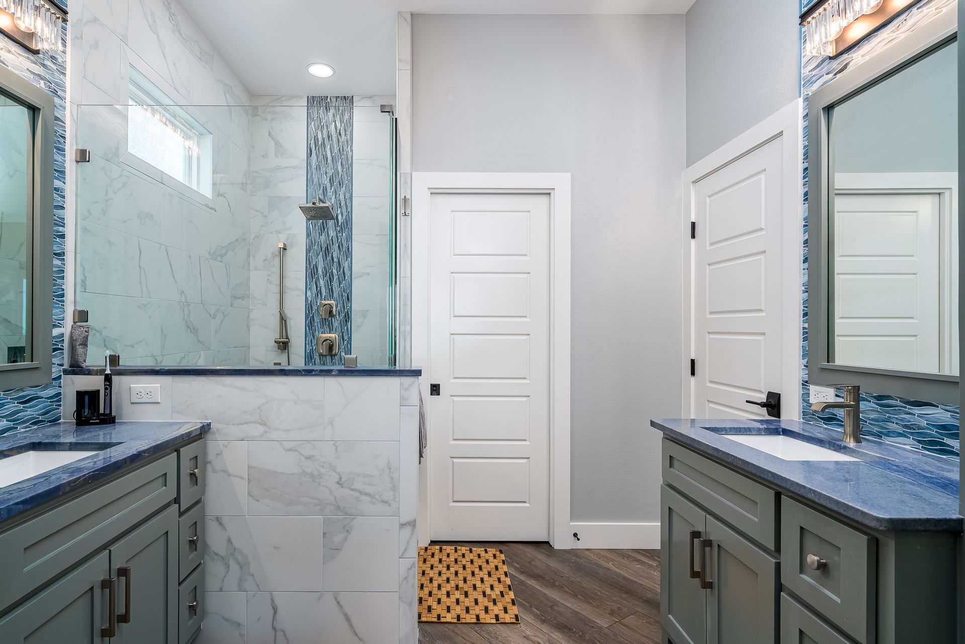 A bathroom with two sinks and a walk in shower.