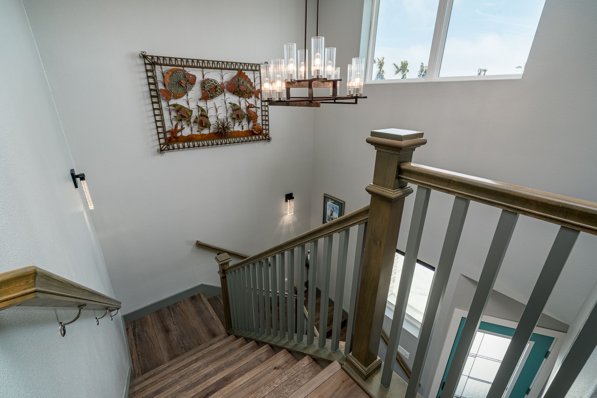 A staircase with a wooden railing and a chandelier hanging from the ceiling.