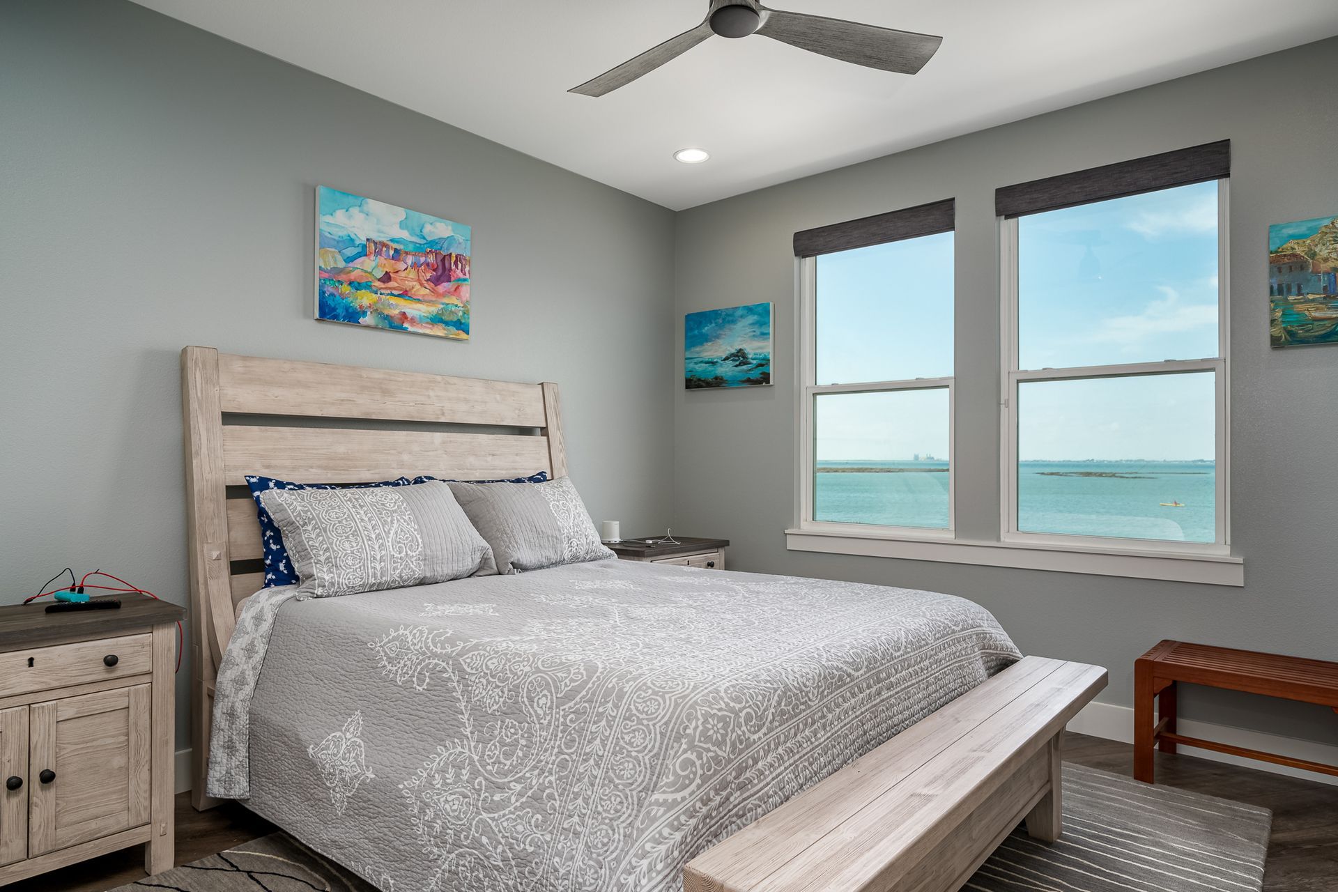 A bedroom with a king size bed , a ceiling fan , and a view of the ocean.