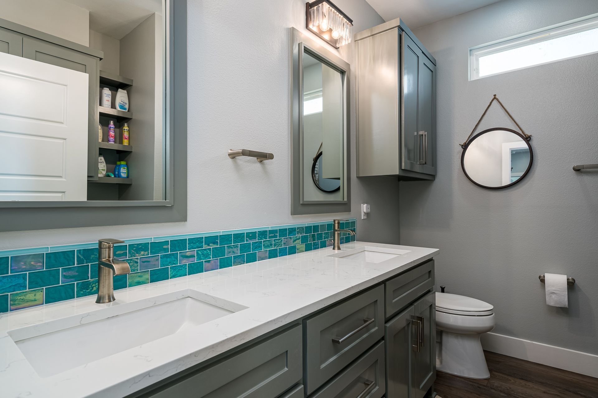 A bathroom with two sinks , a toilet and a mirror.