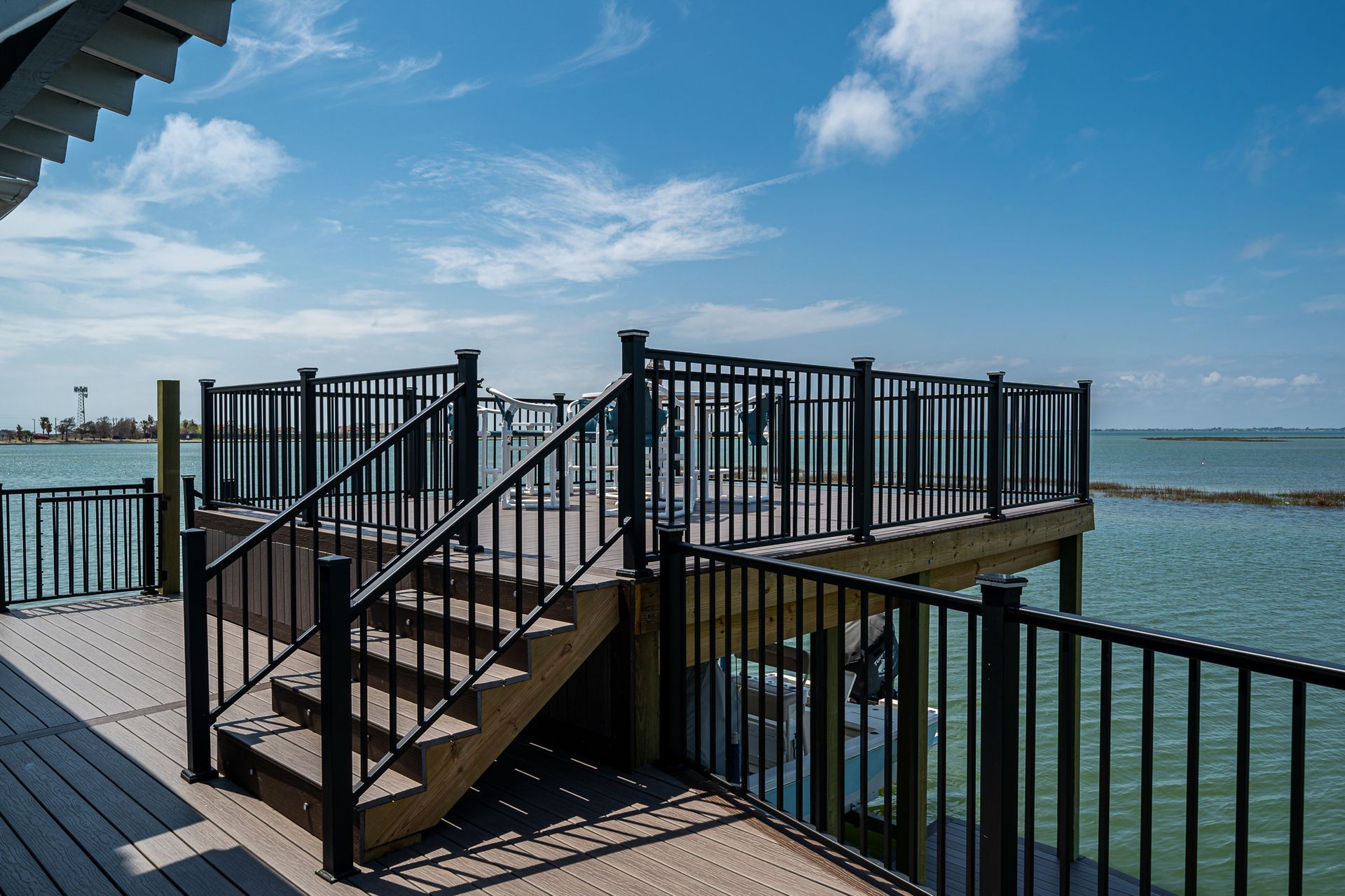 A wooden deck with stairs leading up to it overlooking a body of water.