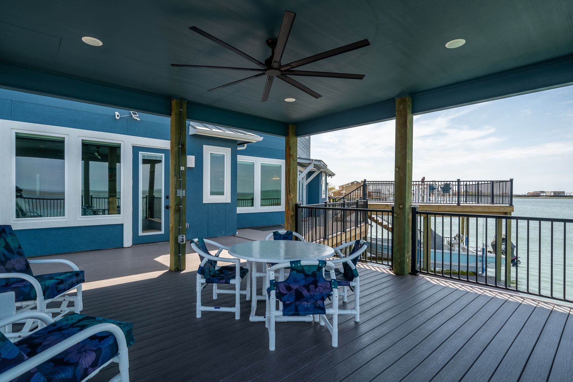 A large deck with a table and chairs and a ceiling fan.
