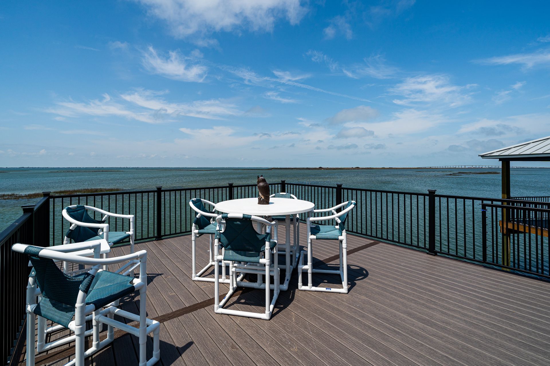 There is a table and chairs on the deck overlooking the ocean.