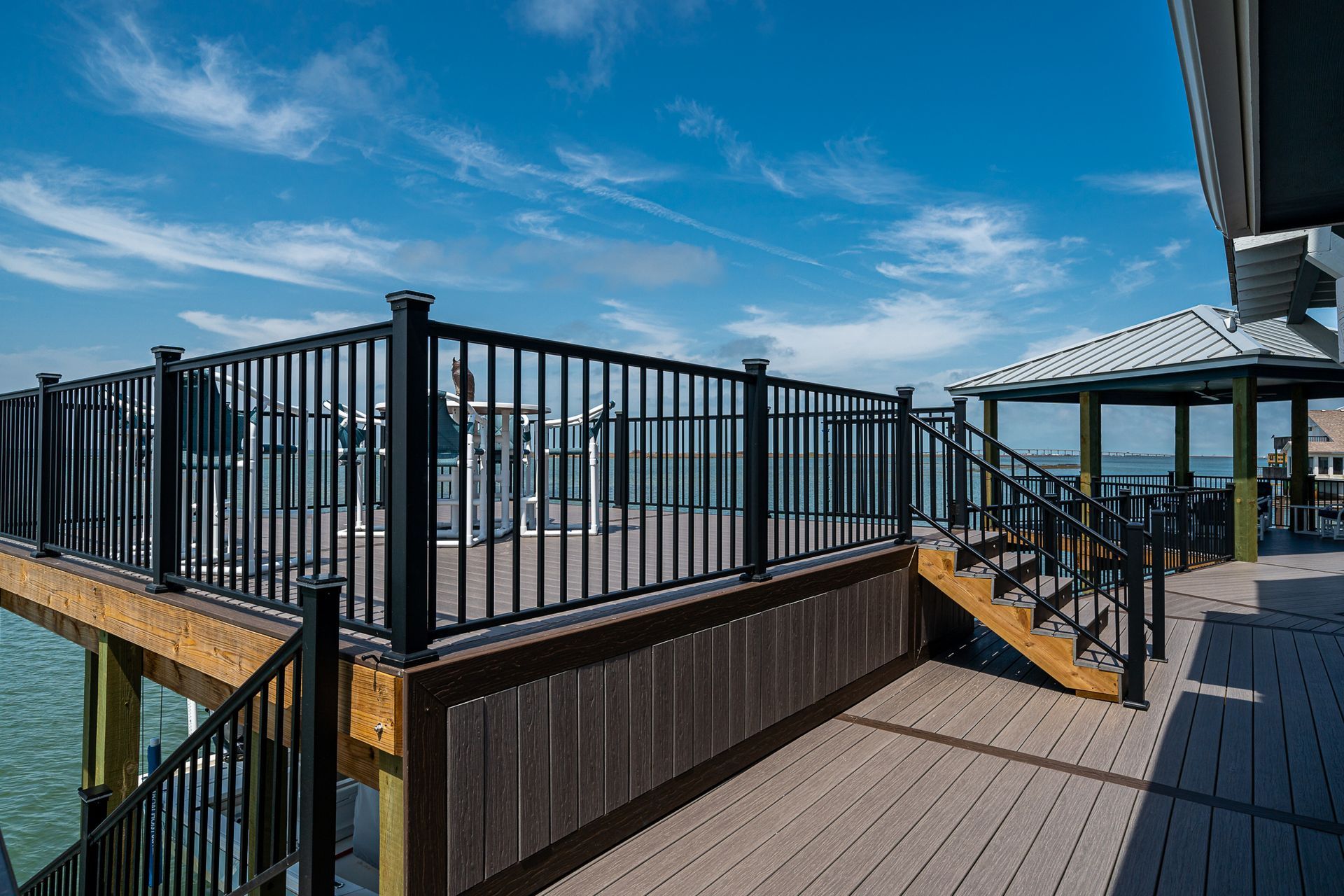 A wooden deck with a black railing overlooking the ocean.
