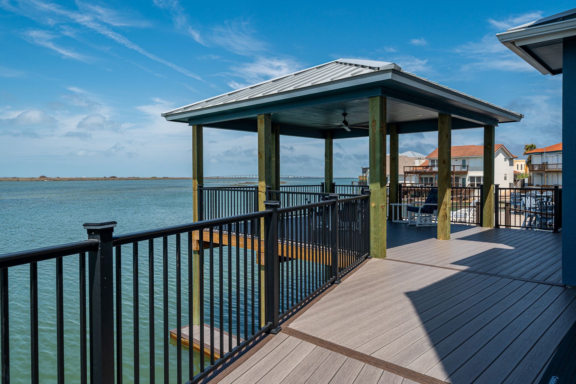 A wooden deck with a gazebo overlooking a body of water.
