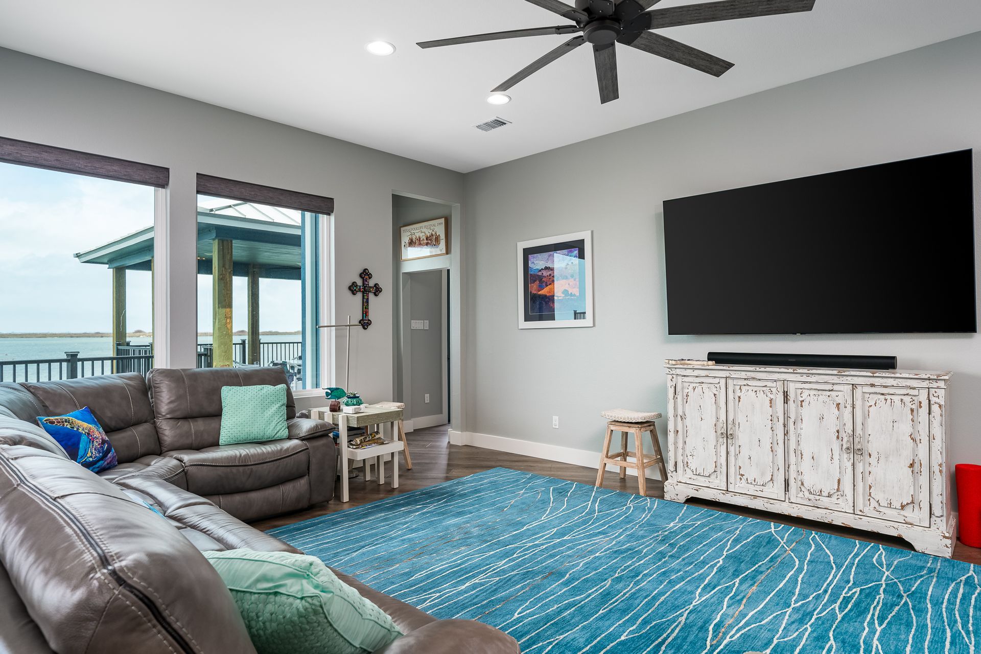 A living room with a couch , rug , television and ceiling fan.