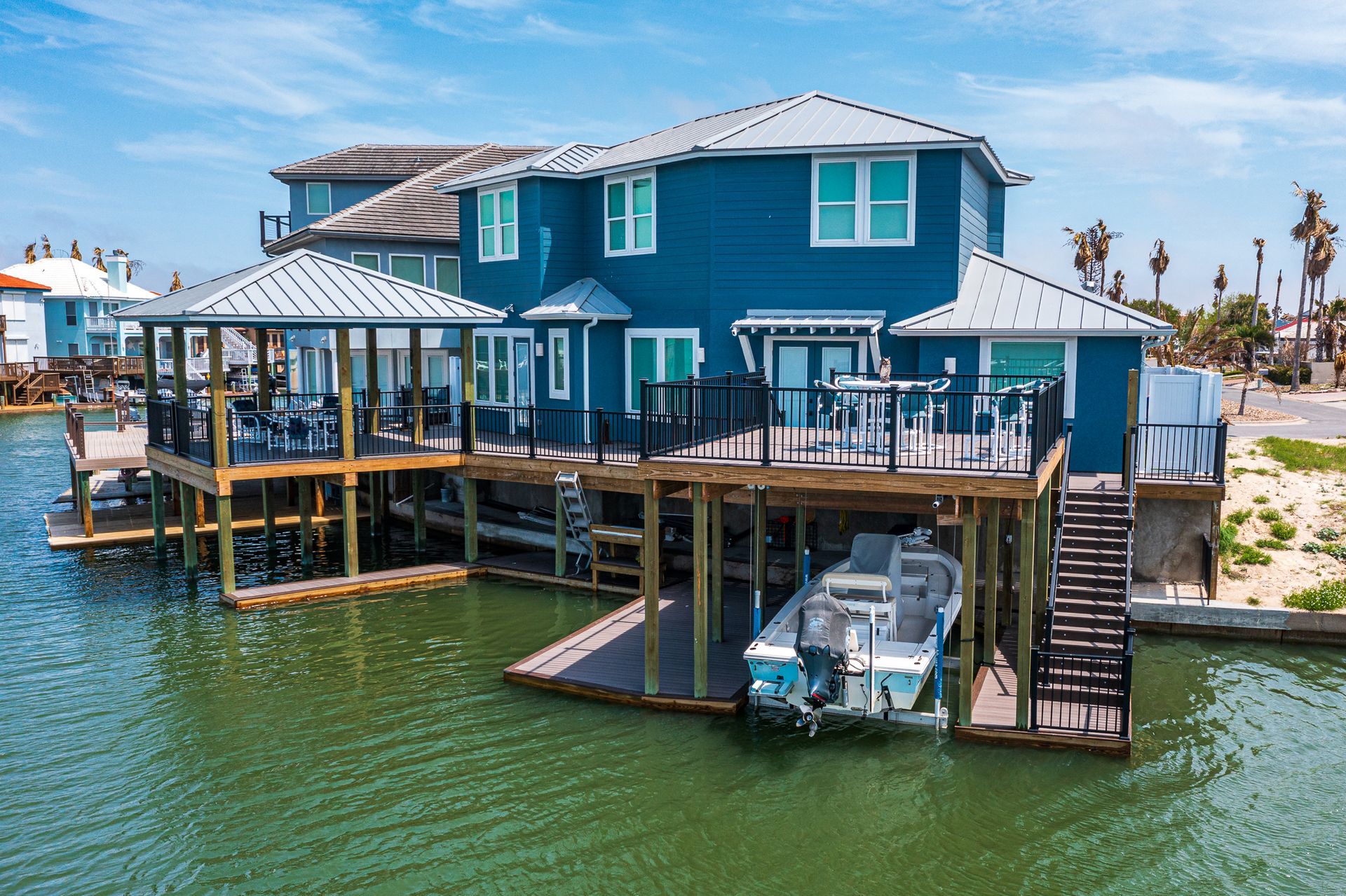 A large blue house with a boat docked in front of it.