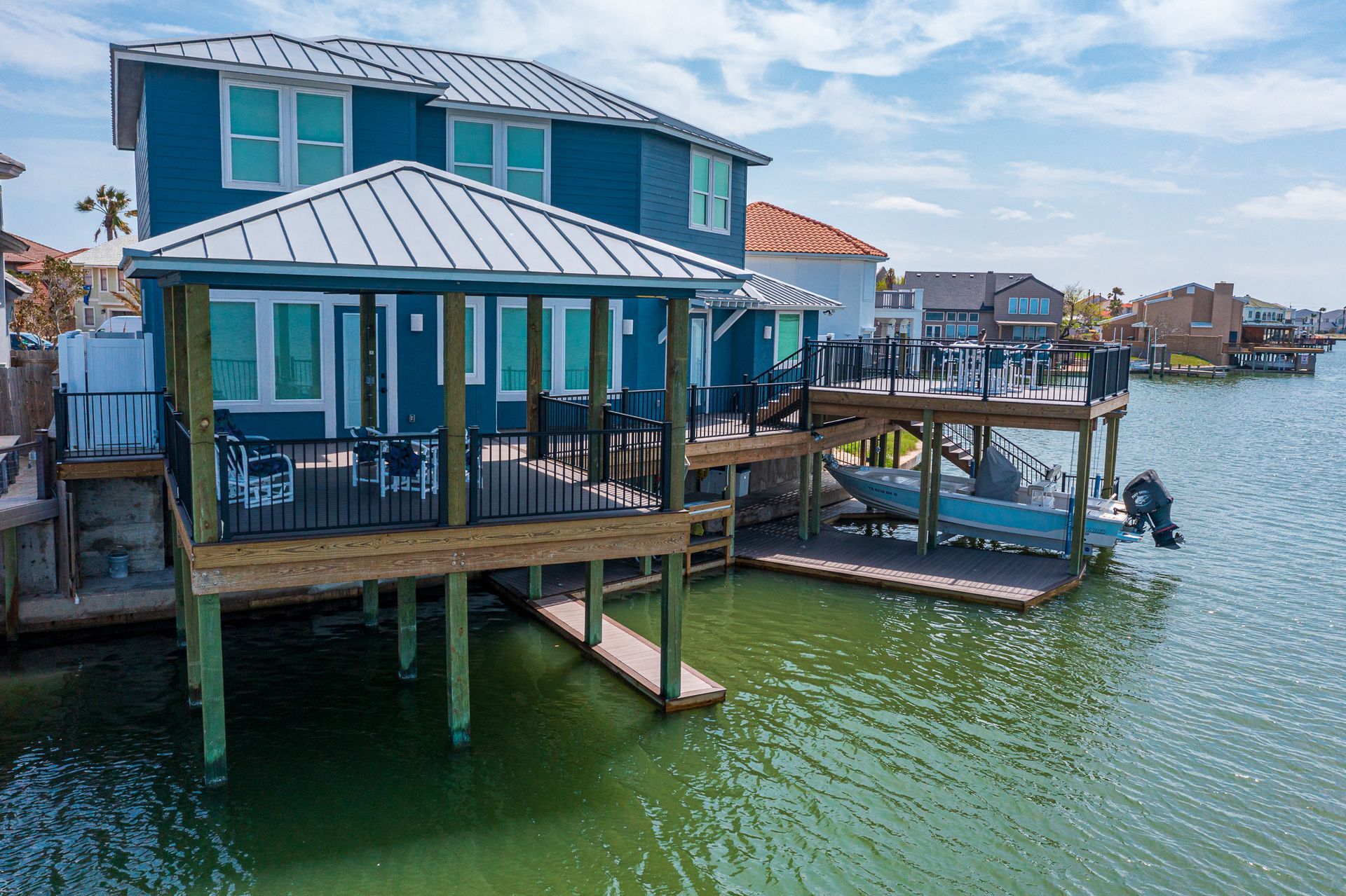 A blue house on stilts overlooking a body of water.