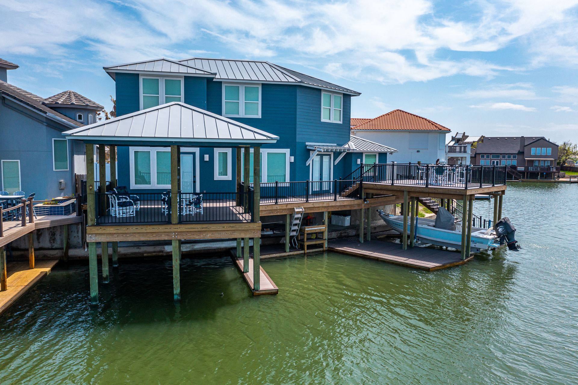 A house on stilts overlooking a body of water with a boat docked in front of it.
