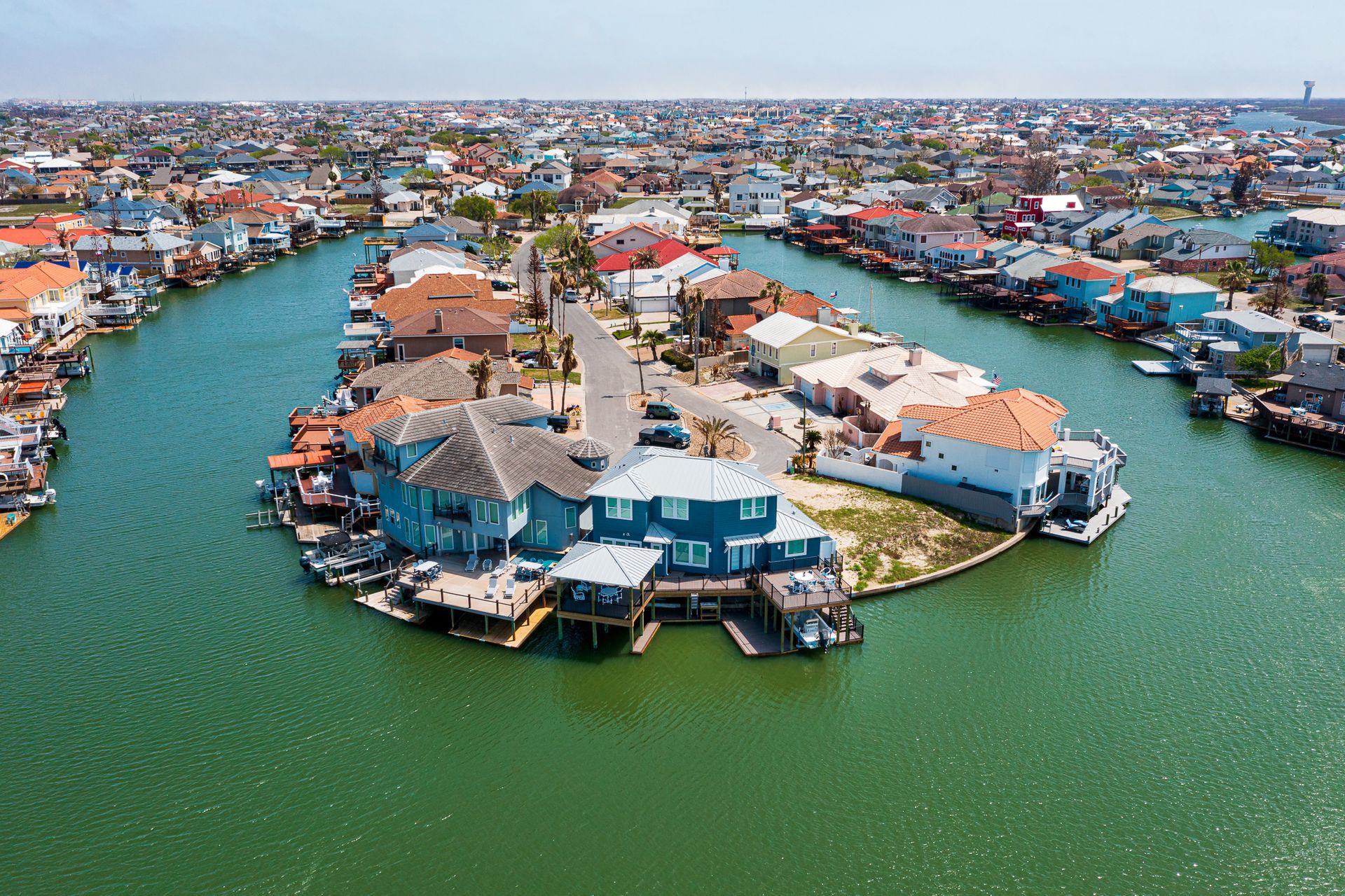 An aerial view of a small island in the middle of a body of water surrounded by houses.