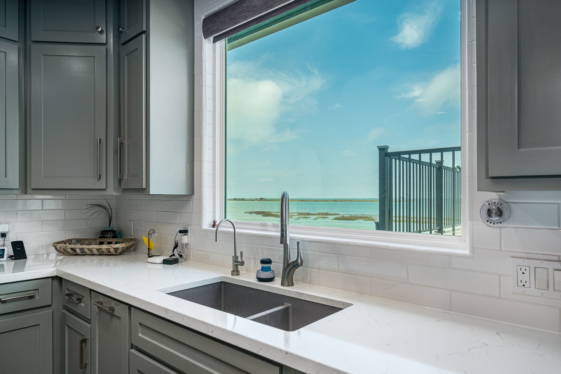 A kitchen with a sink and a window with a view of the ocean.