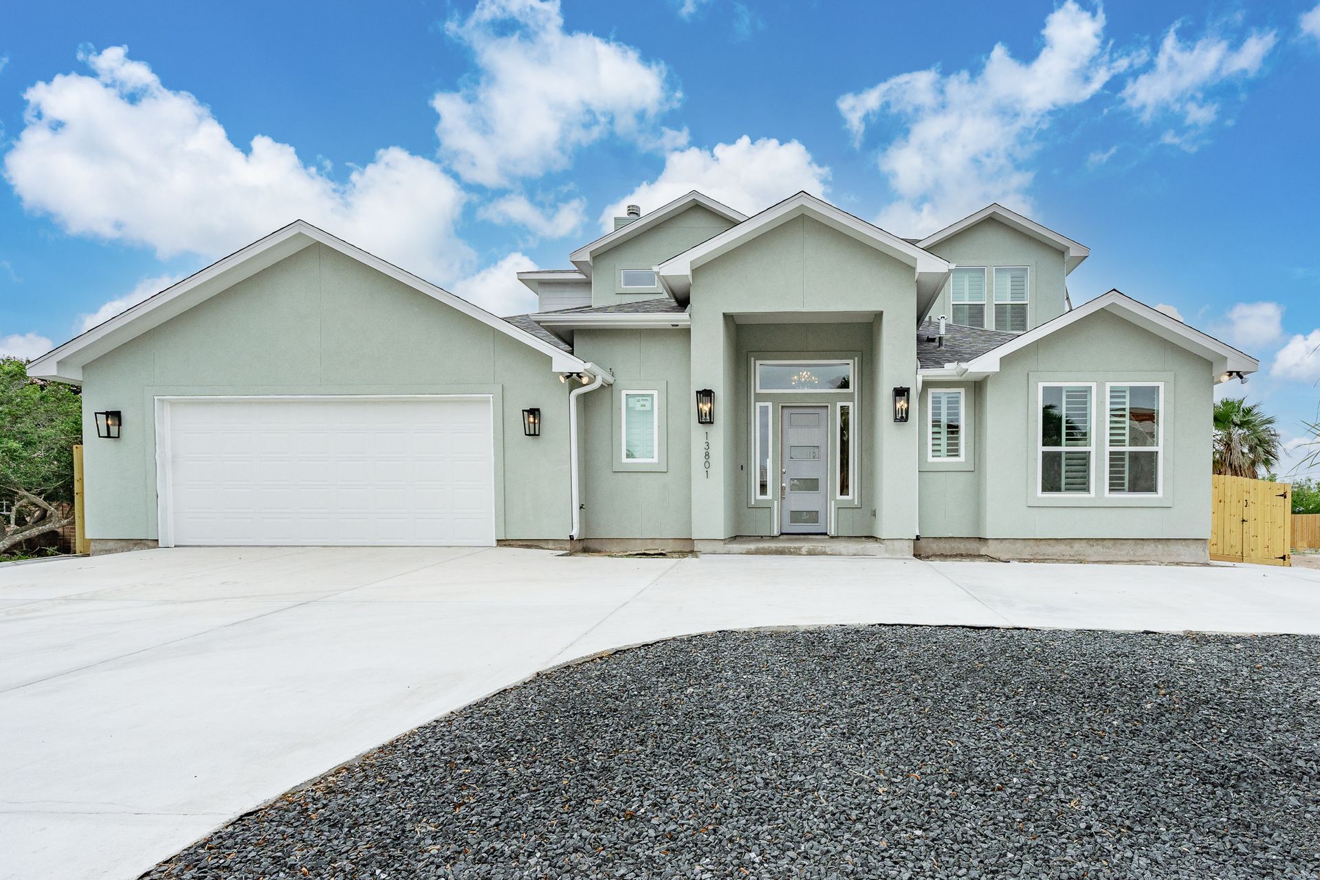 A large house with a white garage door and a gravel driveway