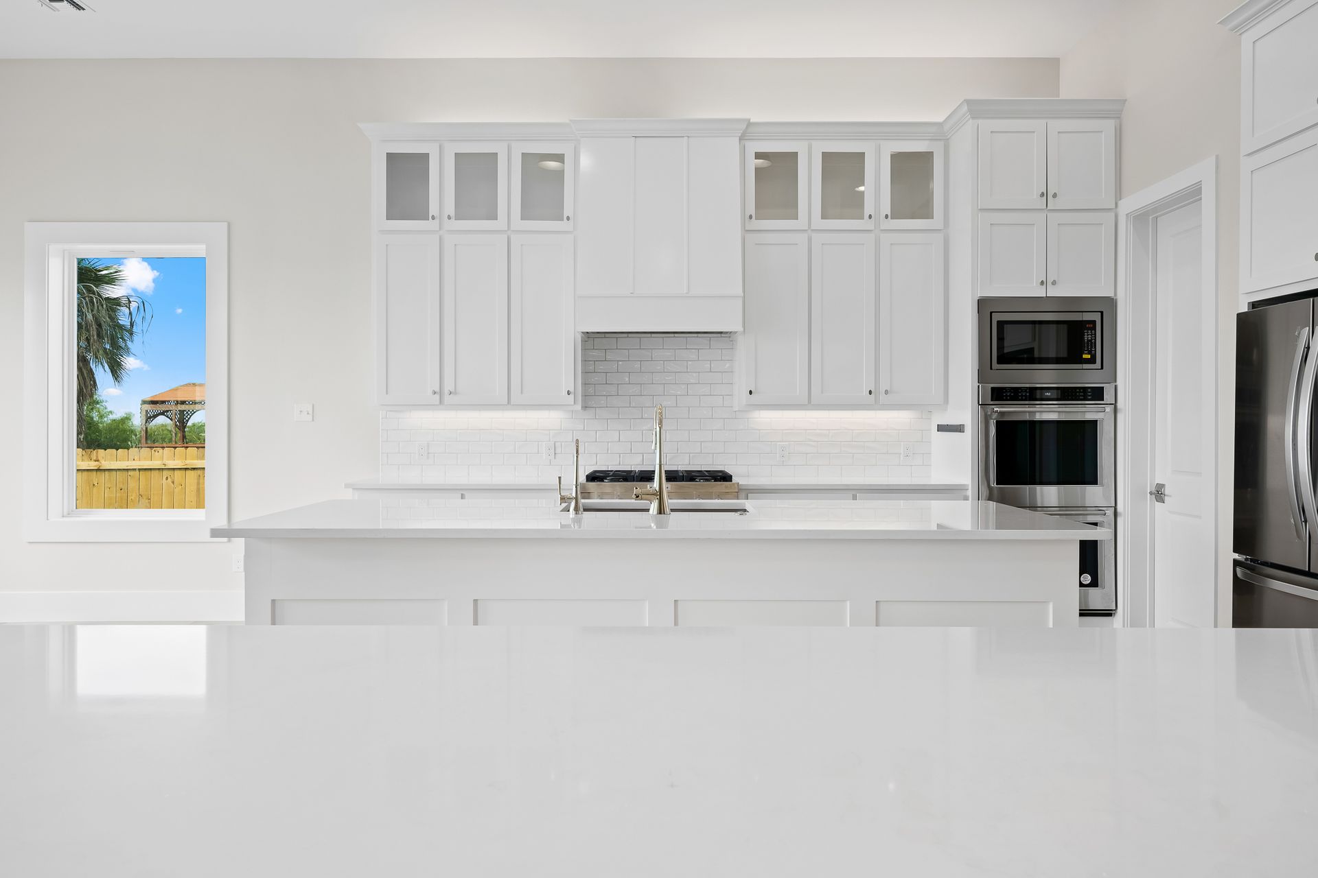 A kitchen with white cabinets , stainless steel appliances , and a large island.