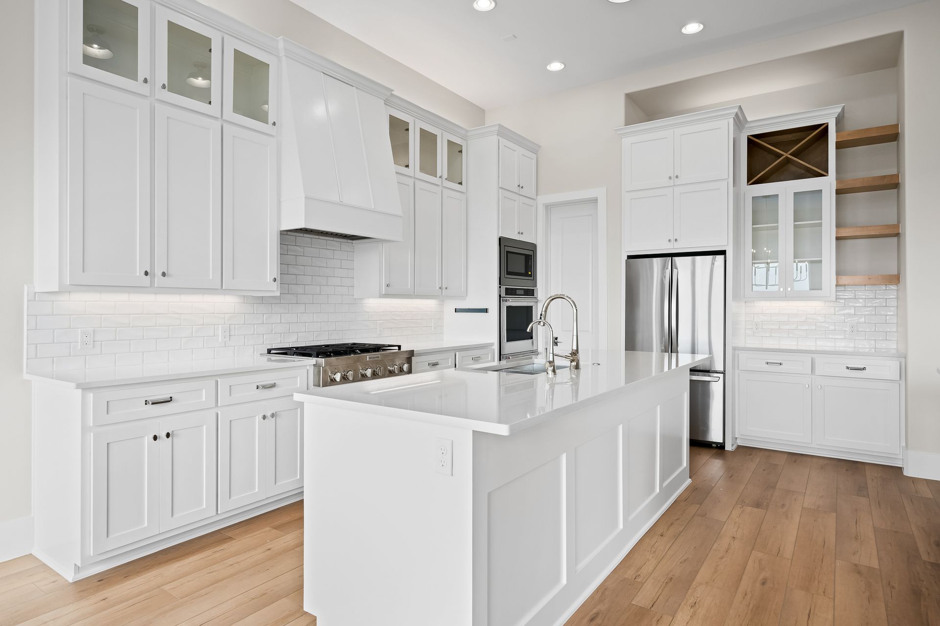 A kitchen with white cabinets , stainless steel appliances , and a large island.