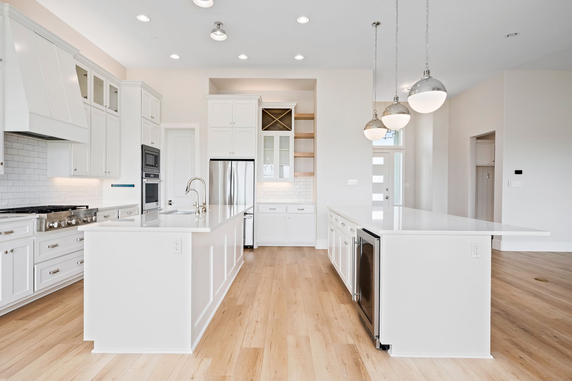 A kitchen with white cabinets , stainless steel appliances , and hardwood floors.