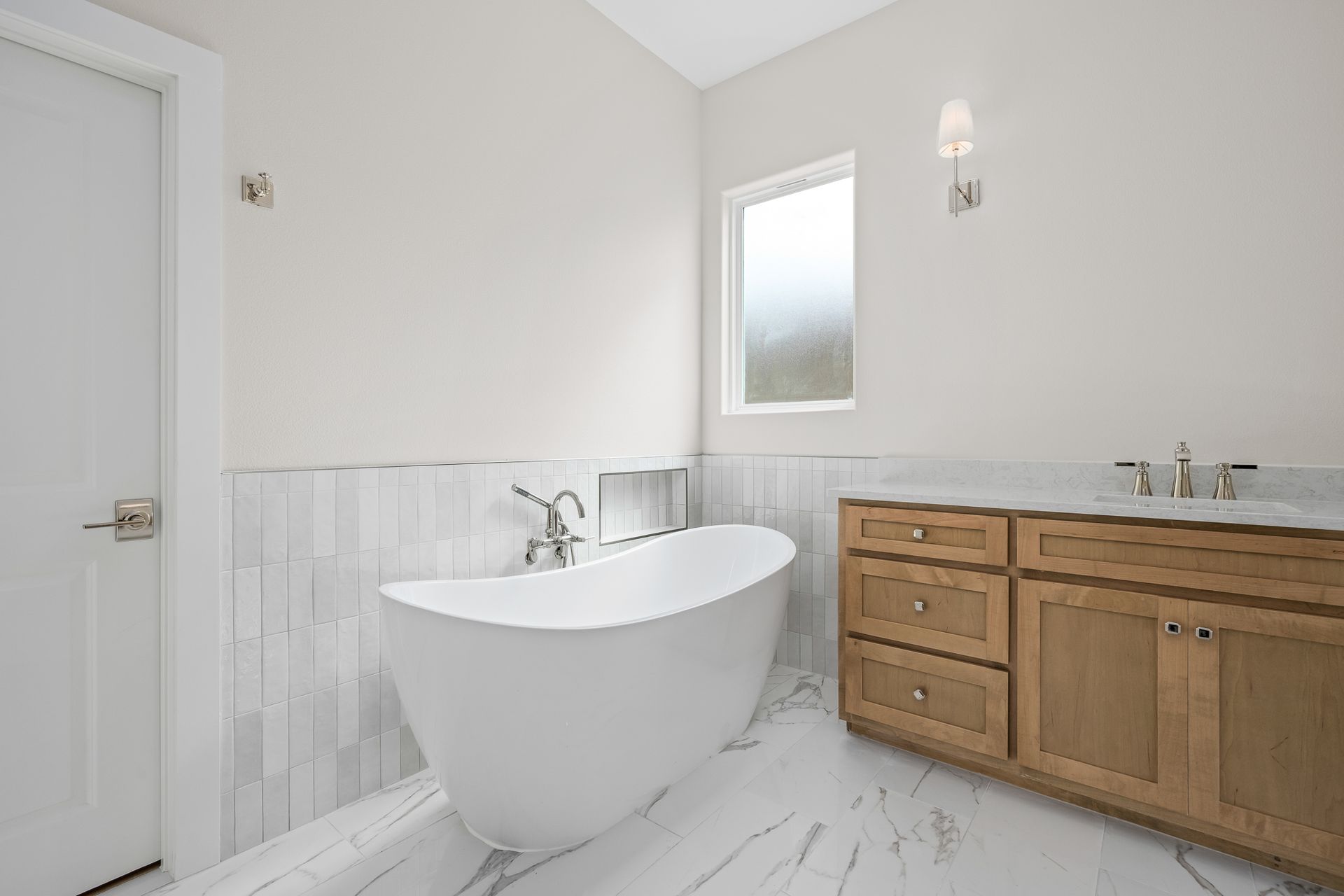 A bathroom with a tub , sink , cabinets and a window.