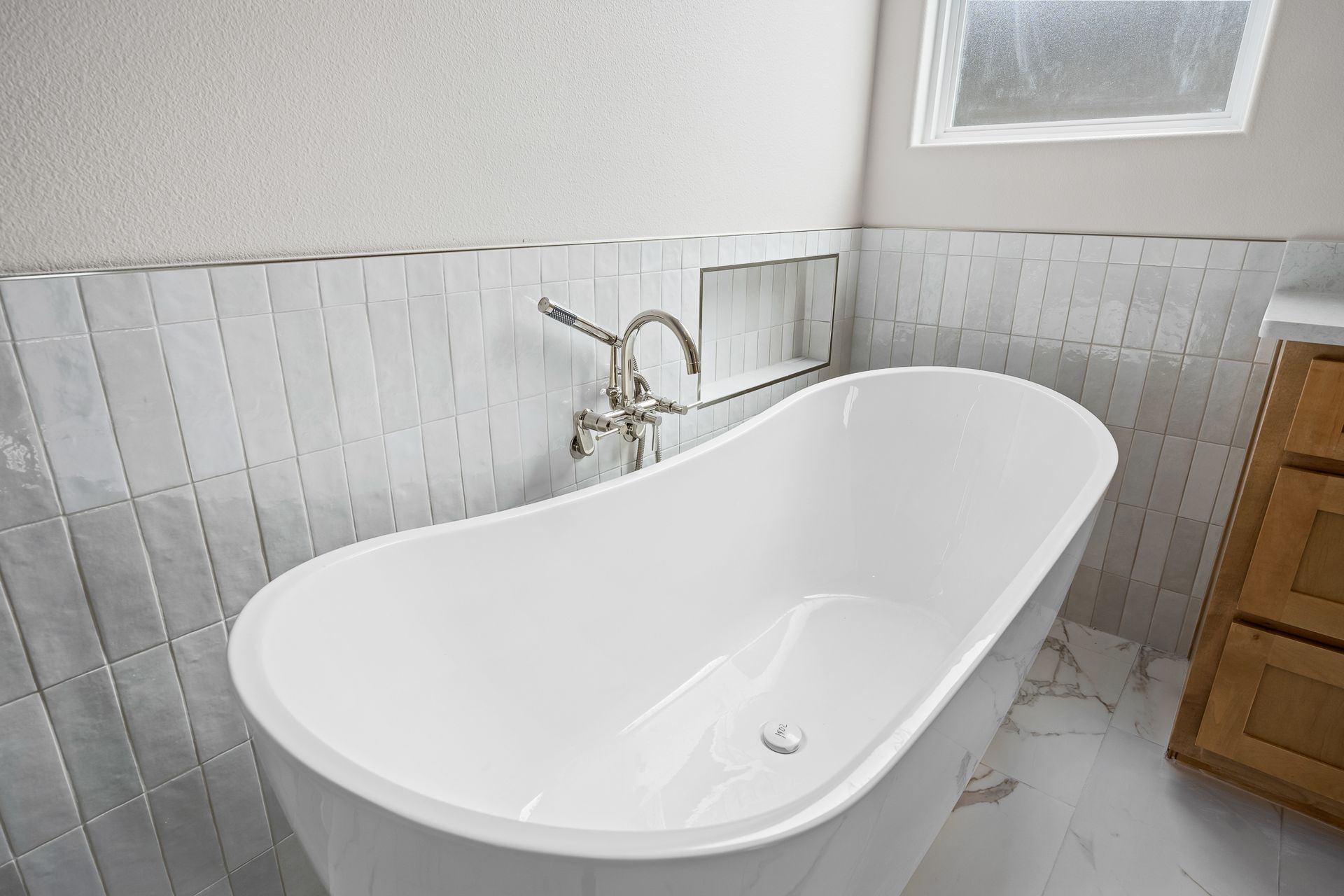 A white bathtub is sitting in a bathroom next to a window.