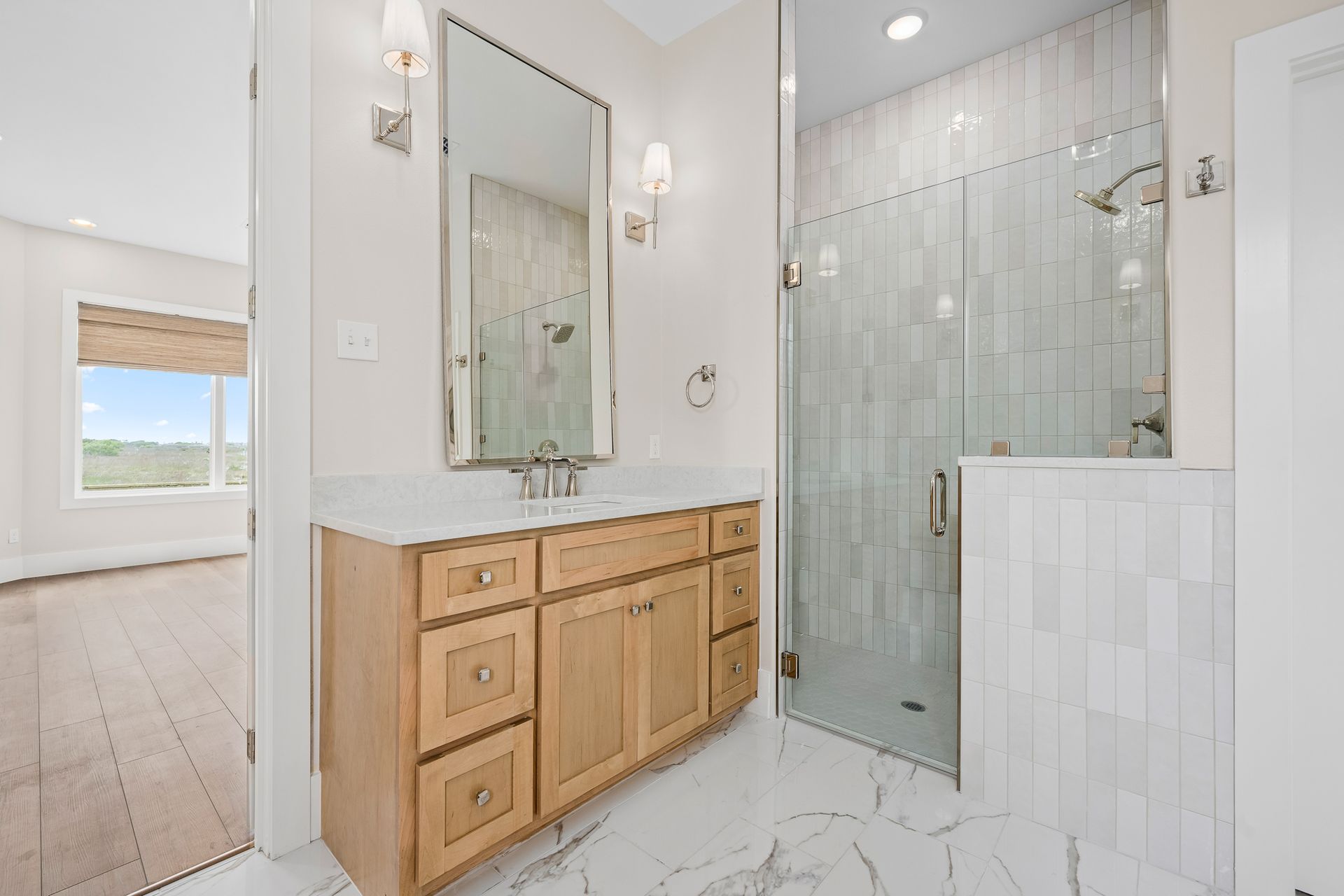 A bathroom with a sink , mirror , and walk in shower.