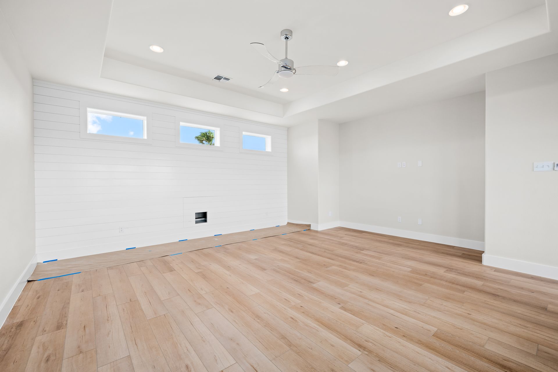 An empty room with hardwood floors and a ceiling fan.