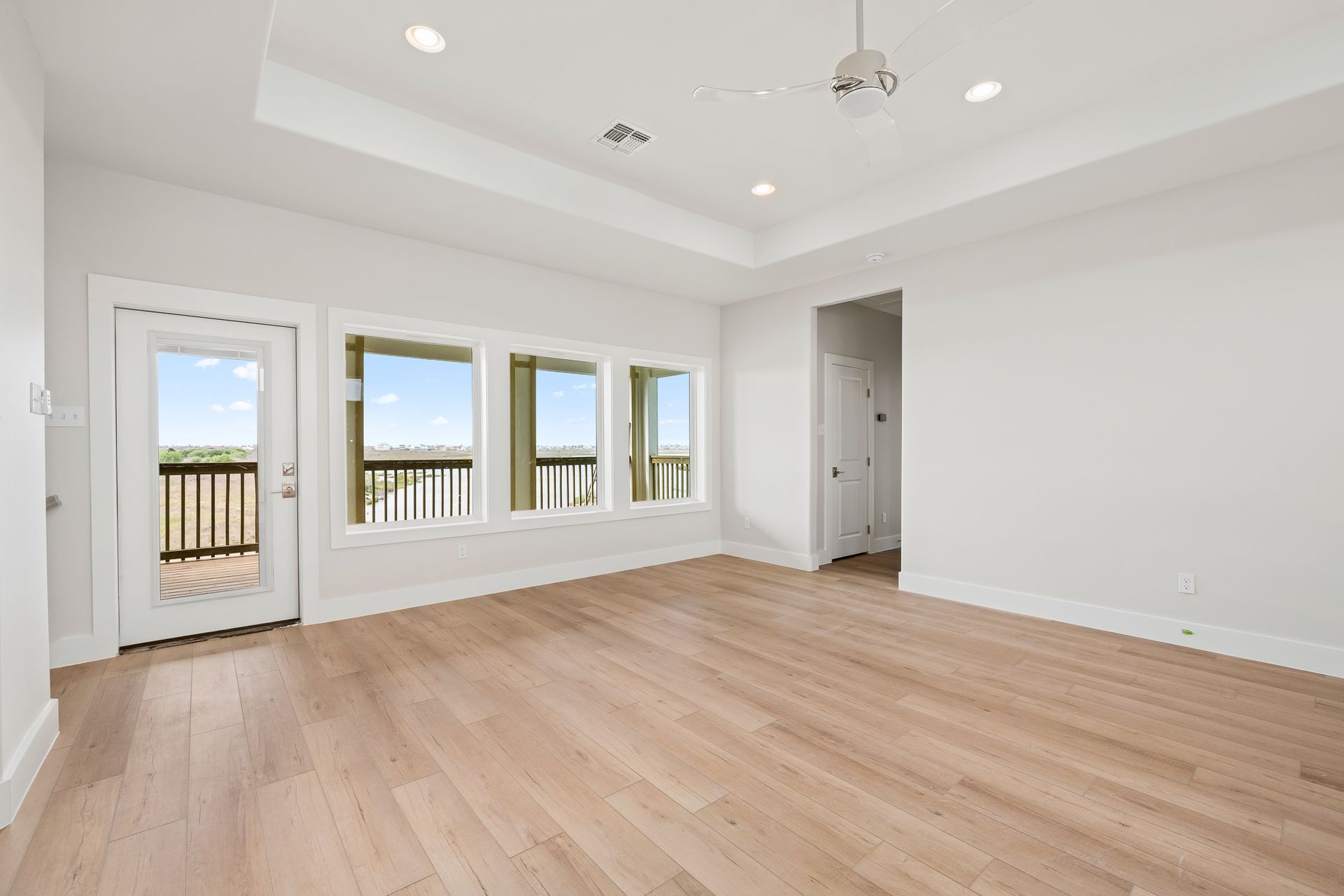 An empty living room with hardwood floors and lots of windows.