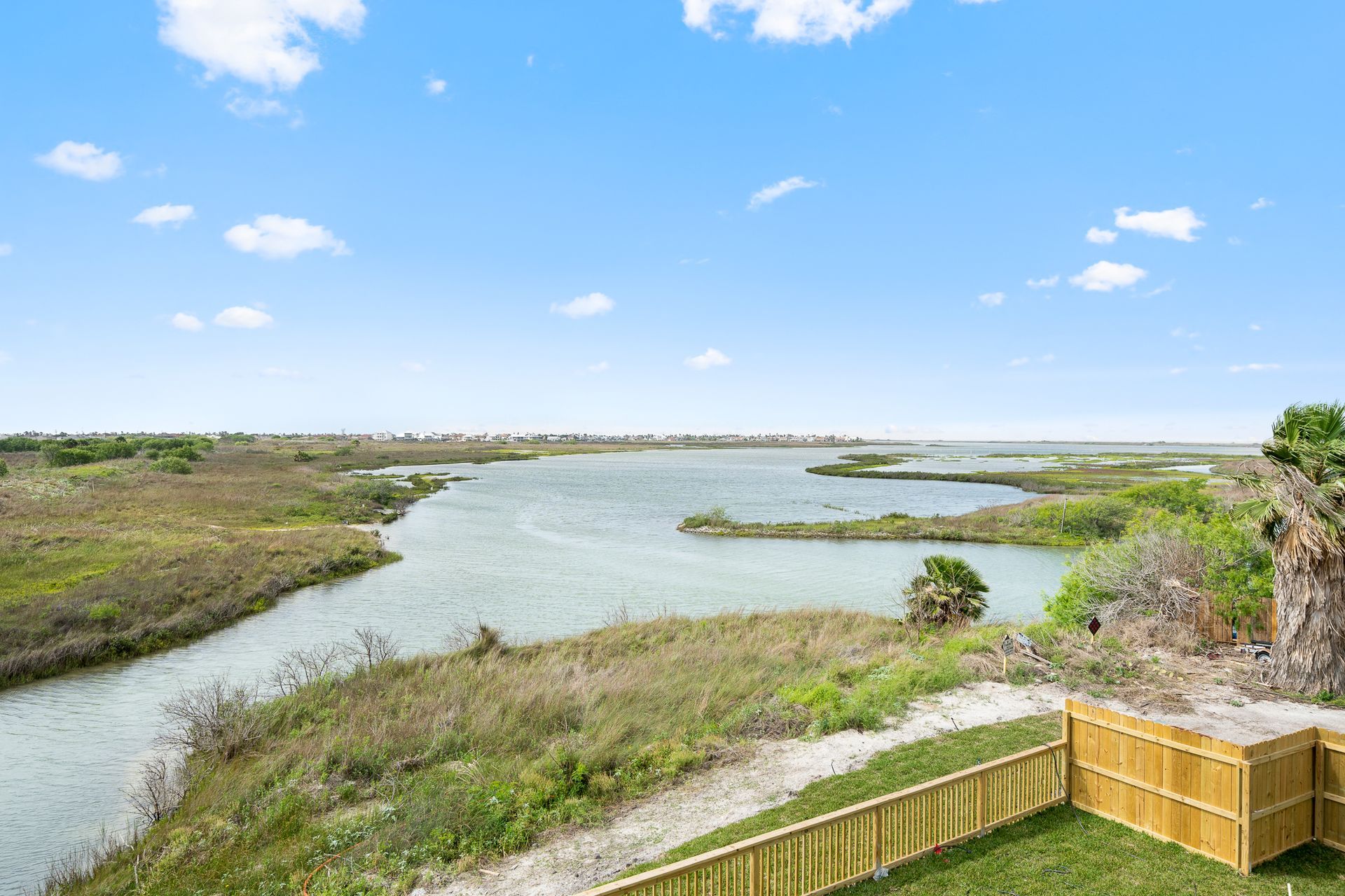 There is a wooden fence in the foreground and a large body of water in the background.