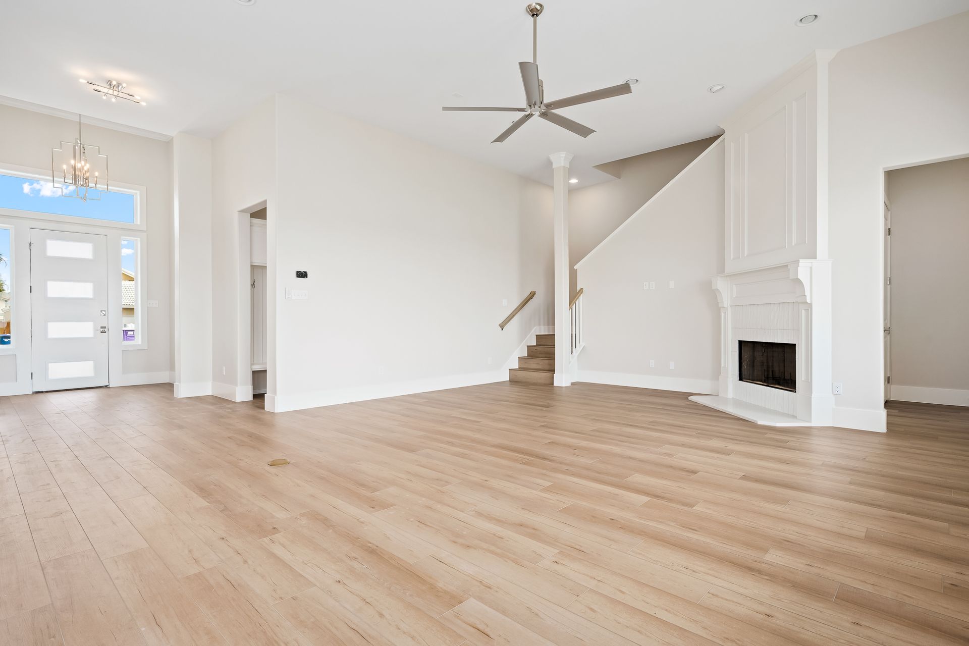 An empty living room with hardwood floors and a ceiling fan