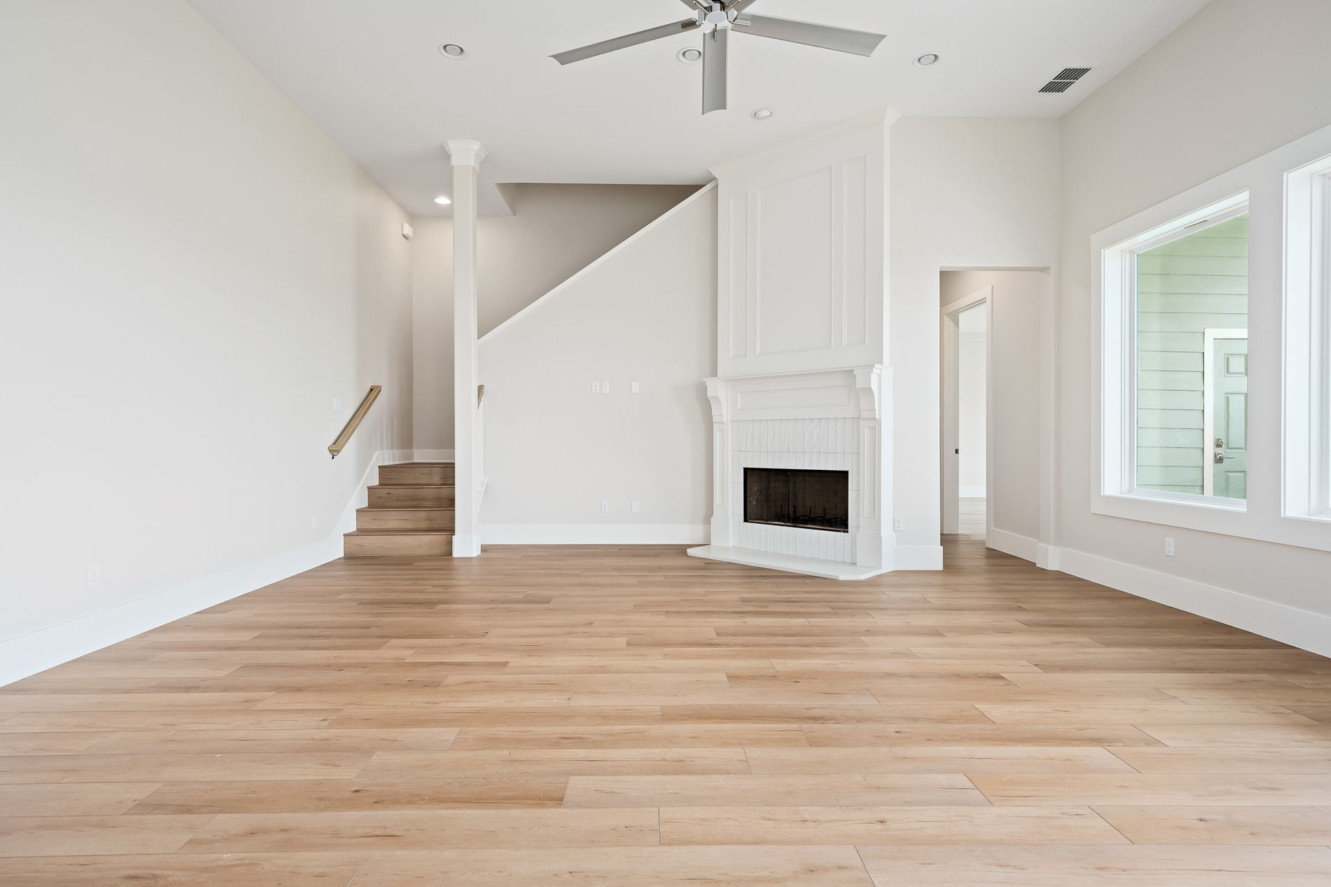 An empty living room with hardwood floors and a fireplace.