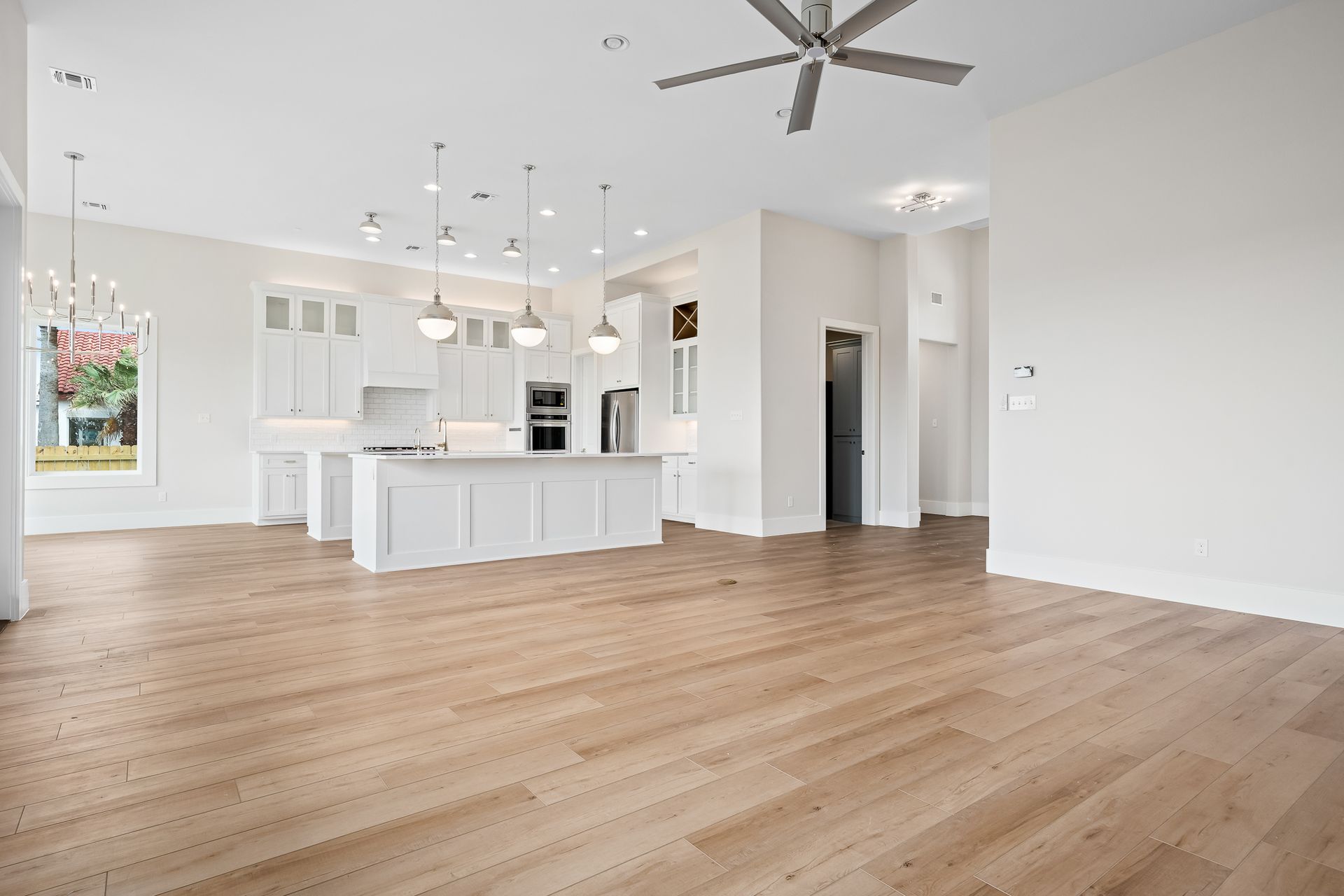 A large empty room with hardwood floors and a ceiling fan.