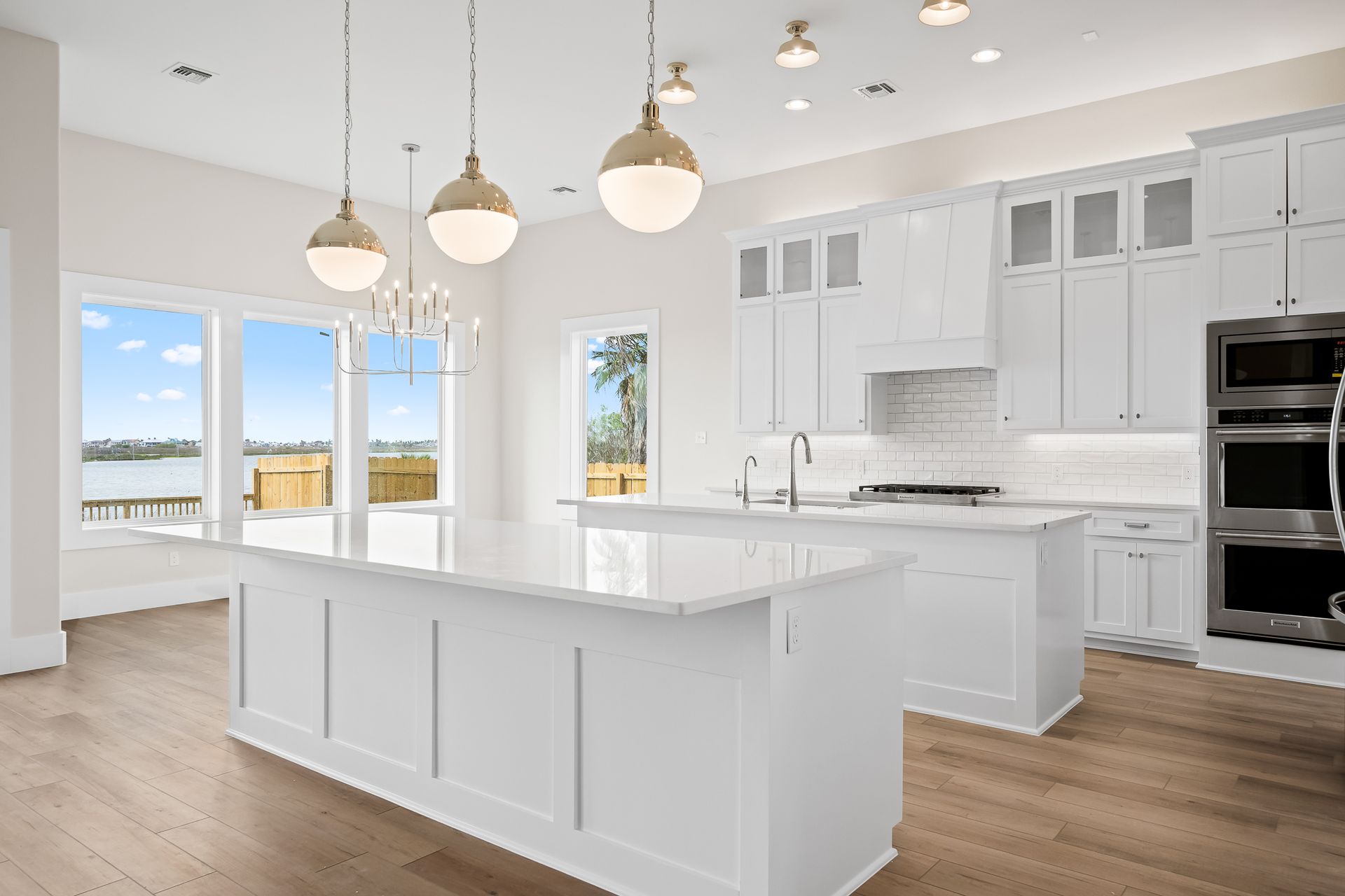 A kitchen with white cabinets , stainless steel appliances , hardwood floors and a large island.