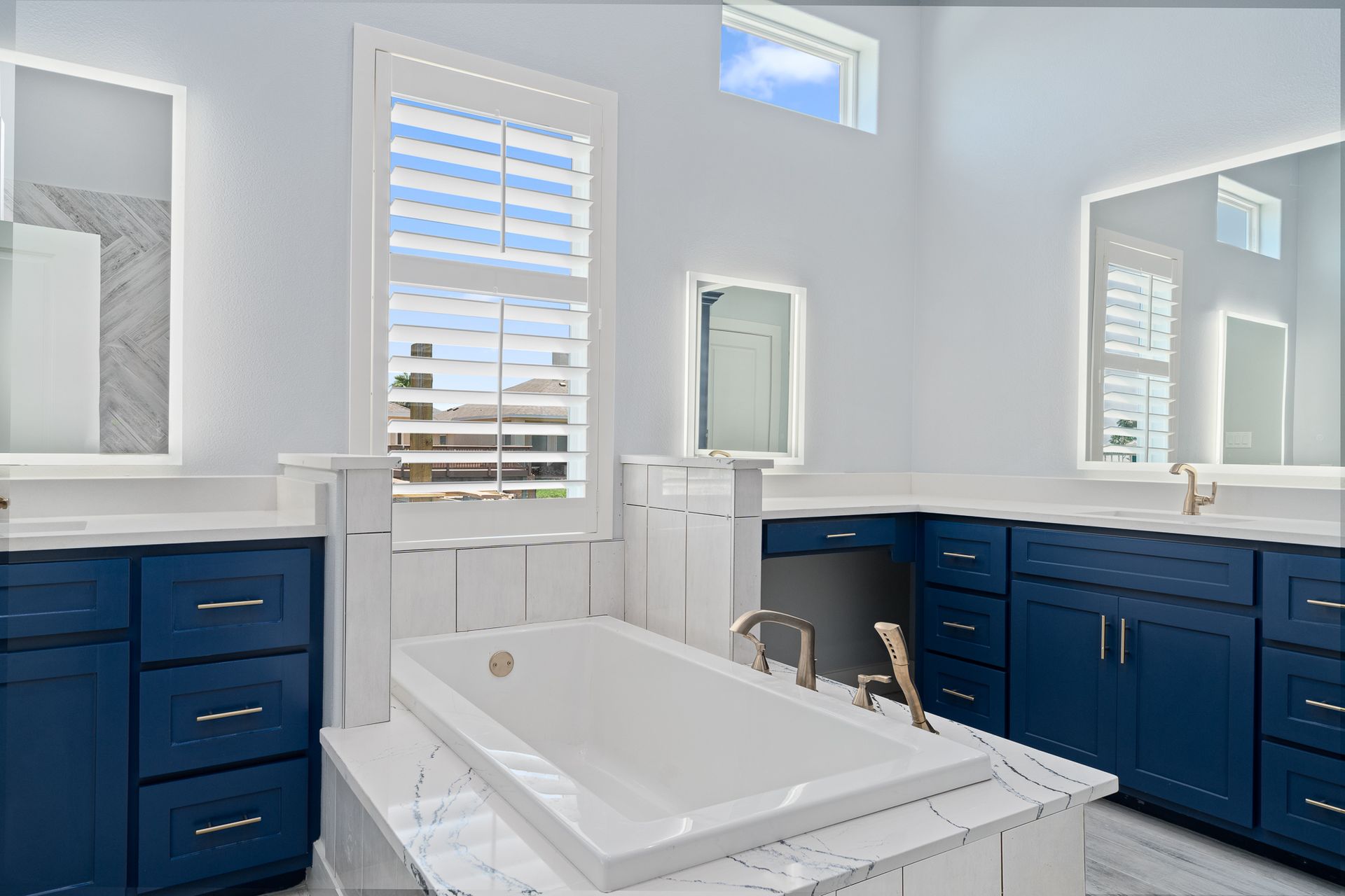 A bathroom with blue cabinets and a white tub.