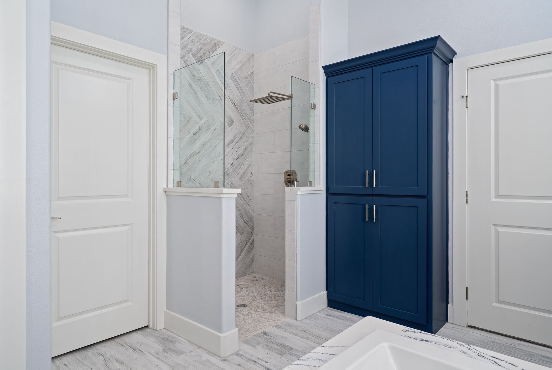 A bathroom with a blue cabinet and a walk in shower.
