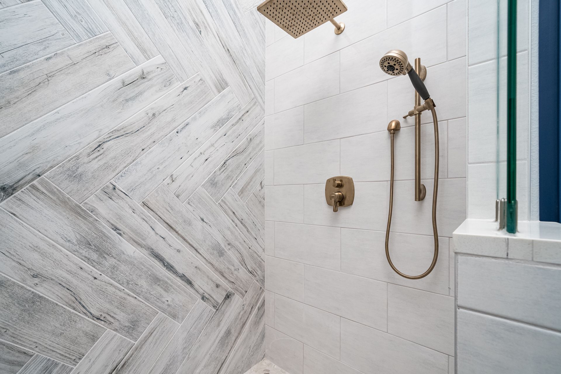 A bathroom with white tiles and a shower head.