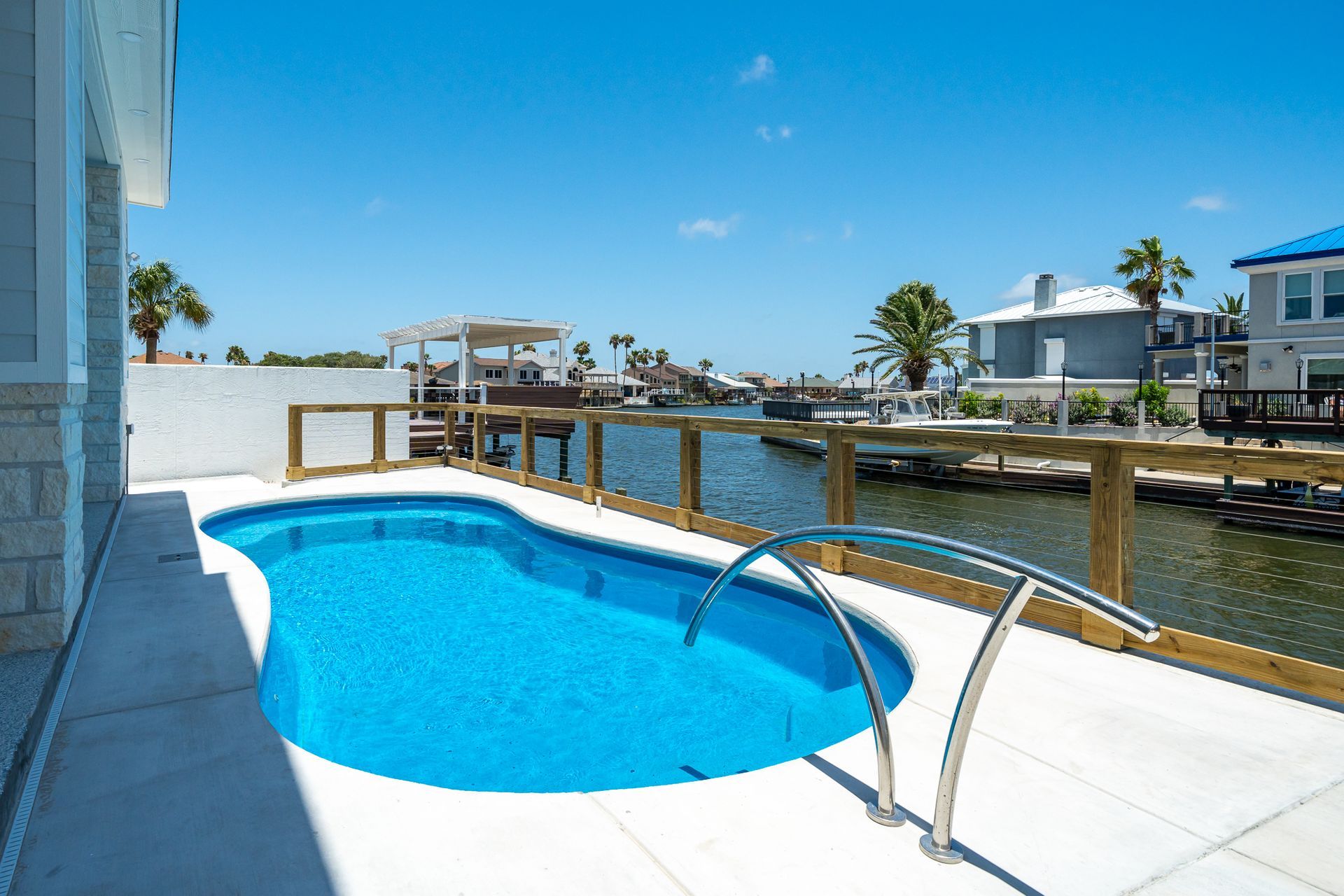 A large swimming pool is surrounded by water and a dock.