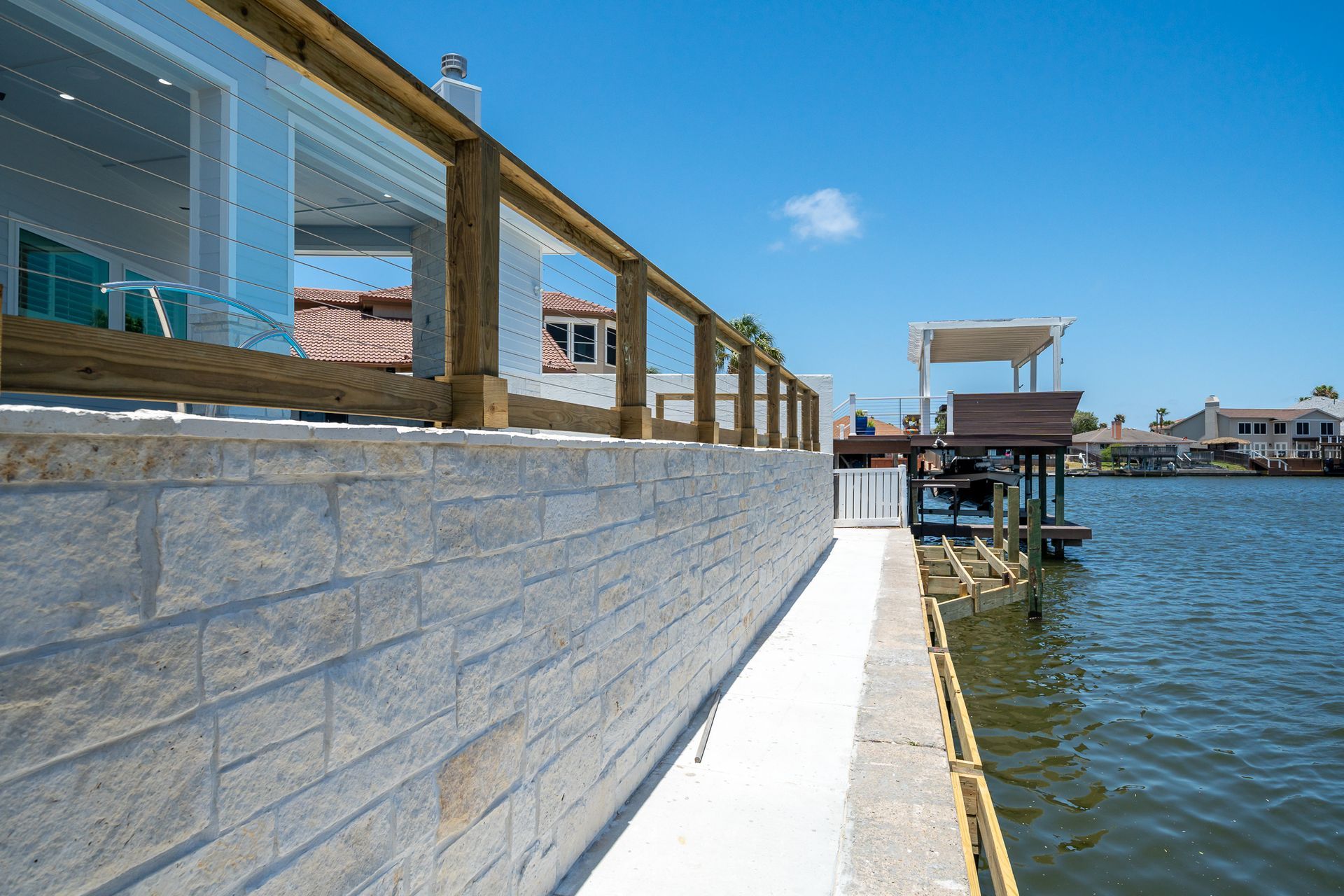 A brick wall with a wooden railing overlooking a body of water.