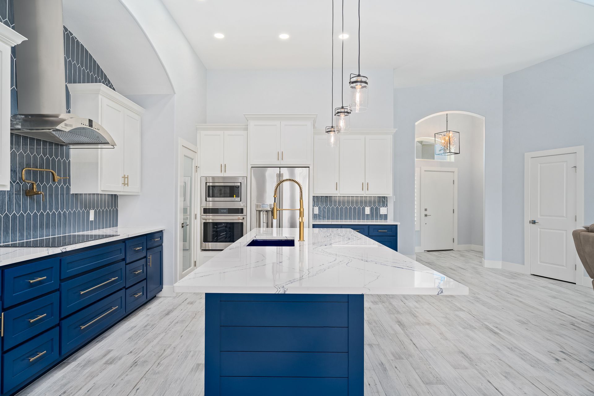 A kitchen with blue cabinets and white counter tops and a large island.