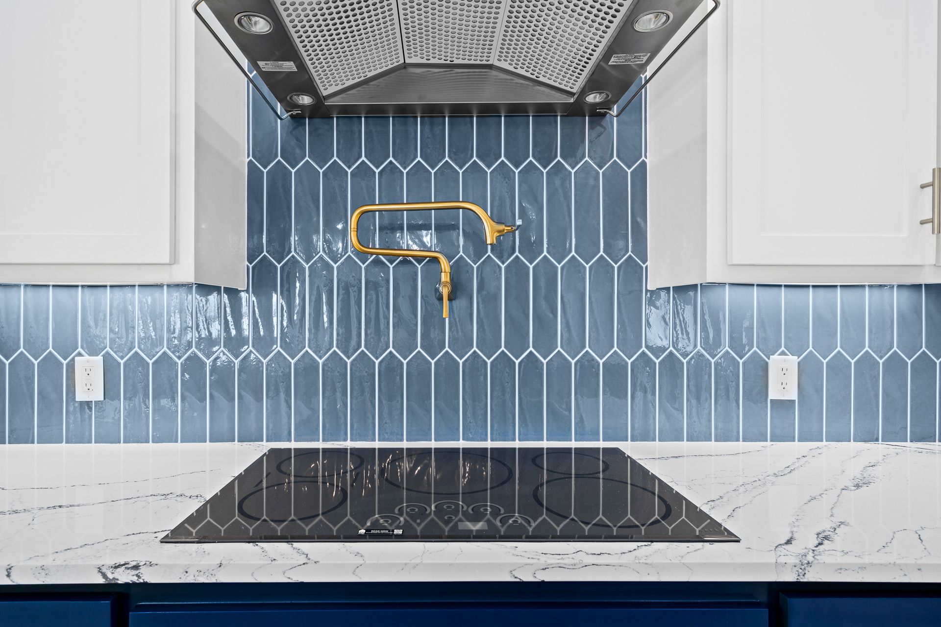 A kitchen with blue tiles and a stove top oven.