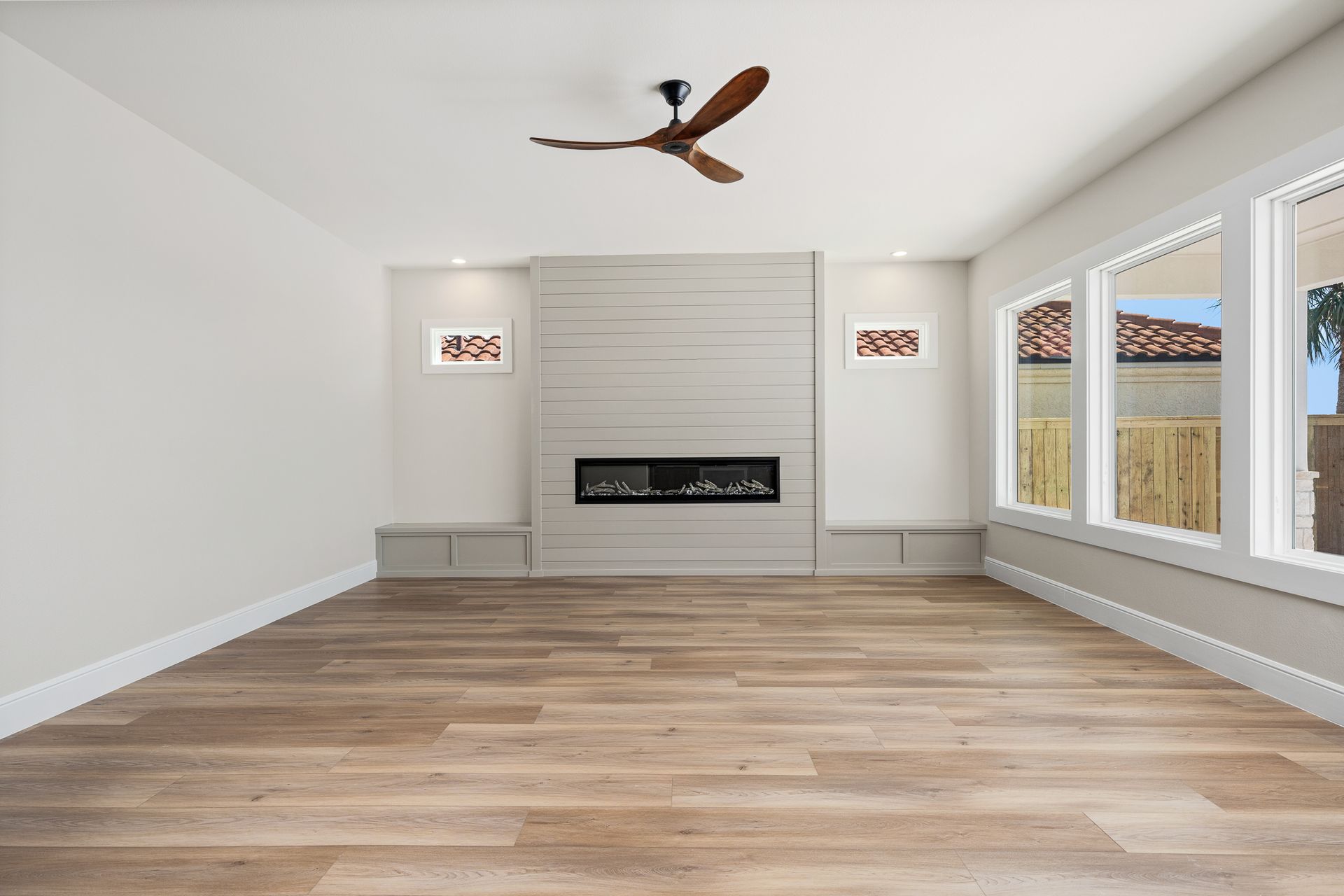 An empty living room with a fireplace and a ceiling fan.