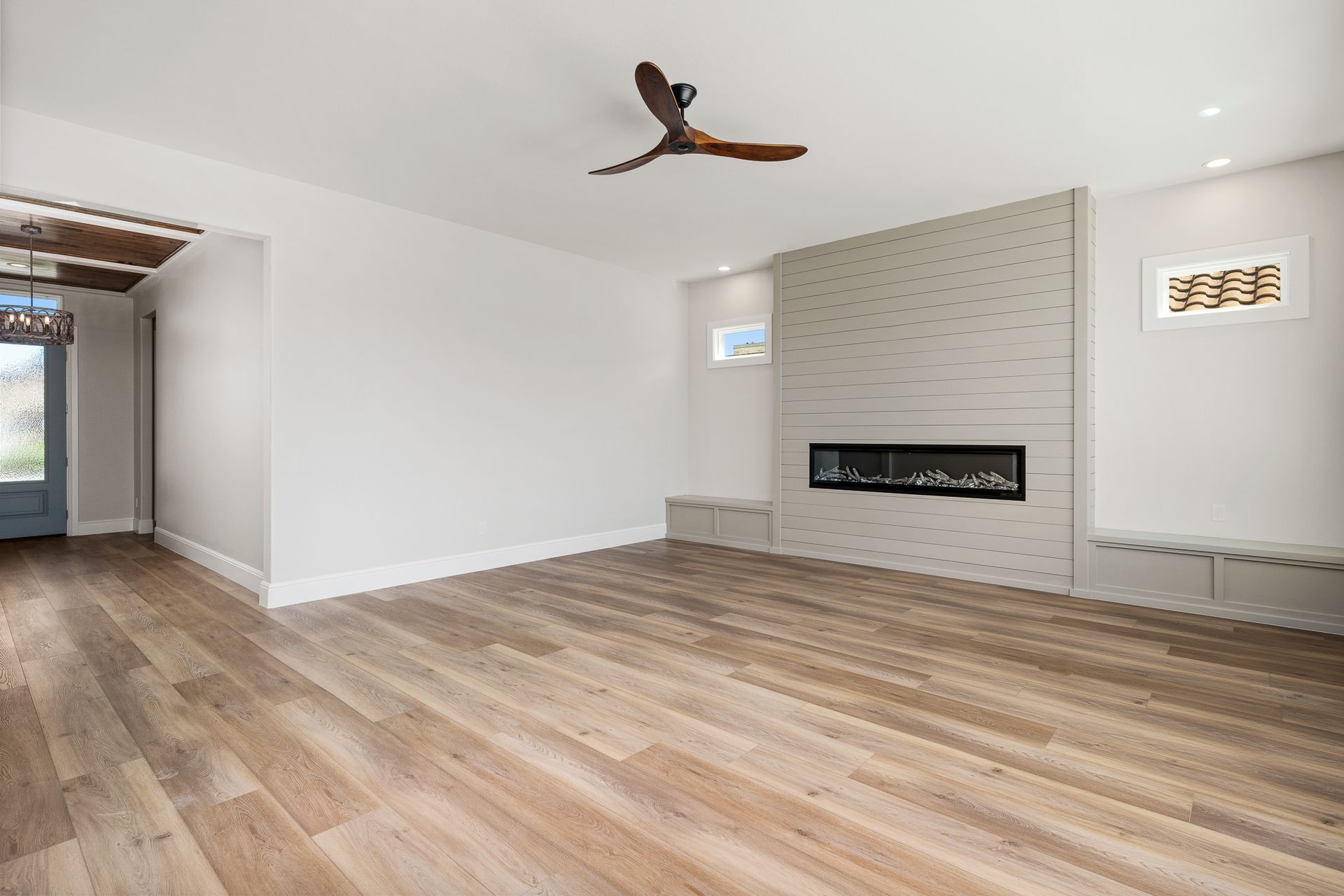 An empty living room with hardwood floors and a ceiling fan.