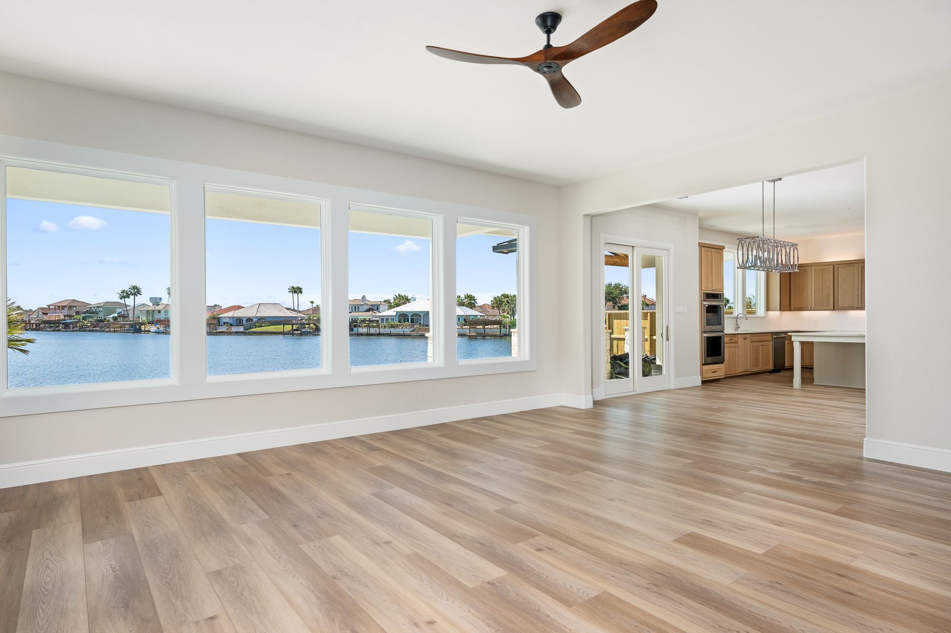 An empty living room with hardwood floors and a ceiling fan.