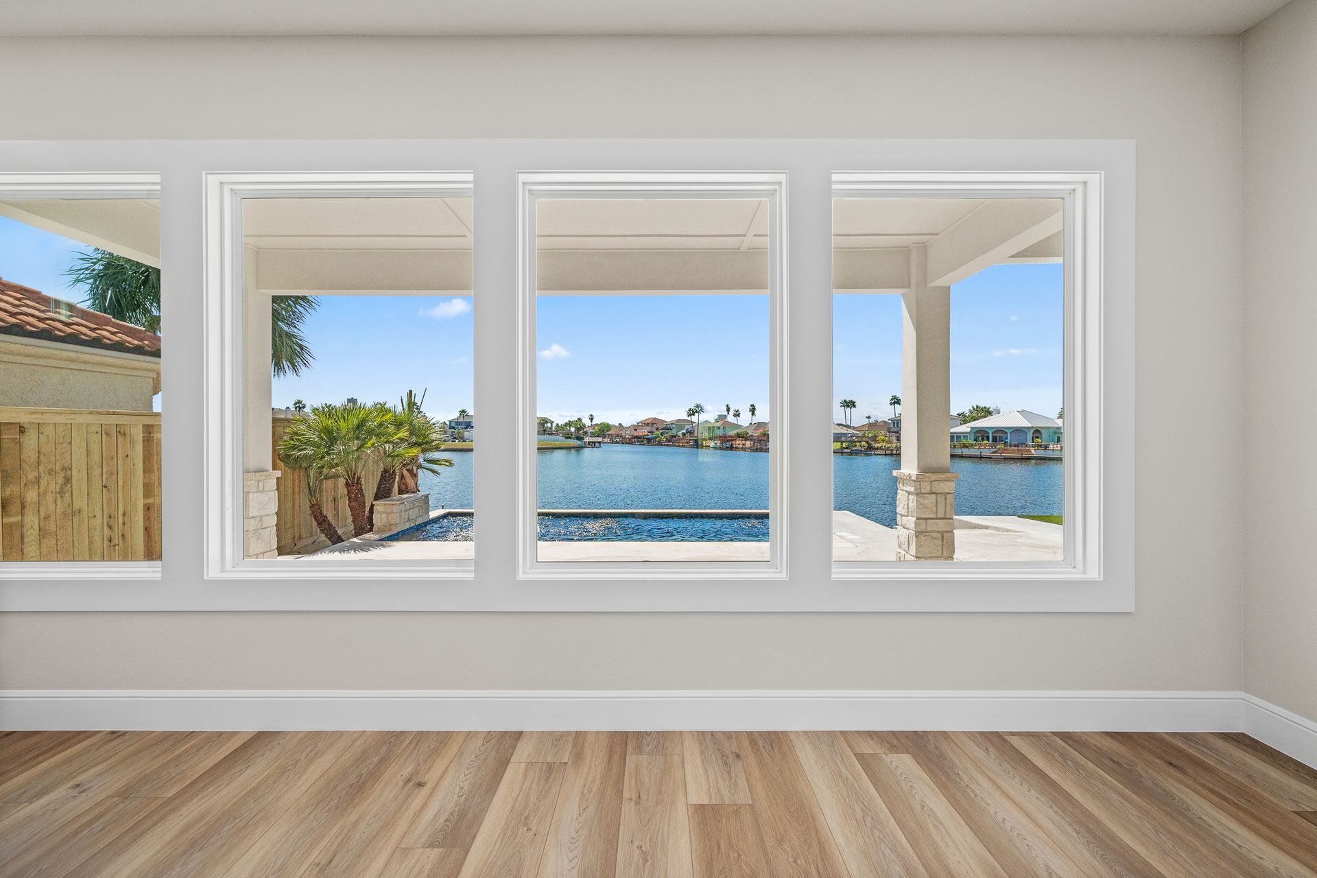 An empty room with three windows and a view of a body of water.