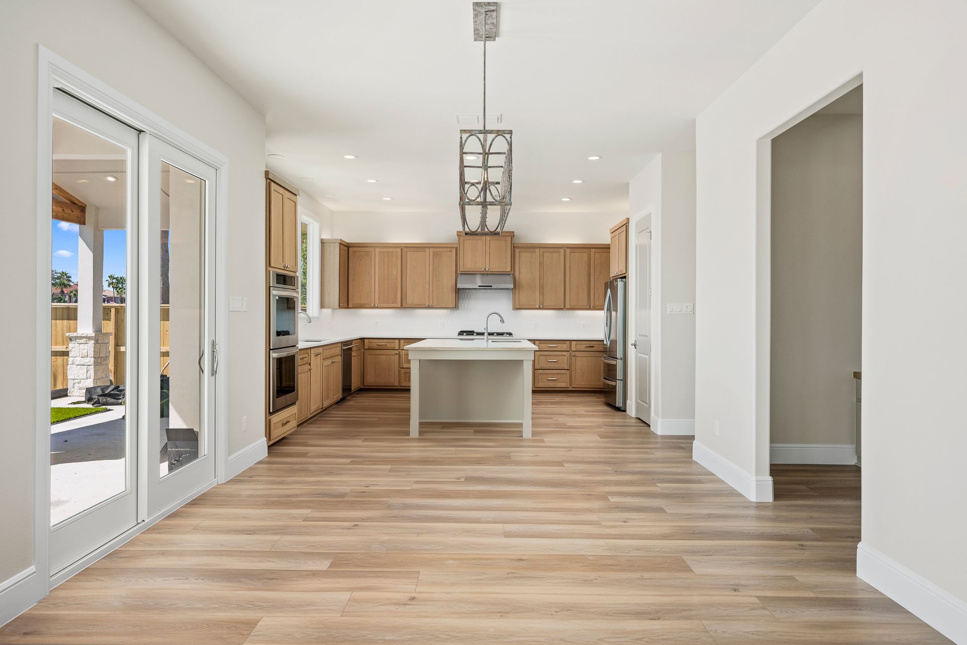 An empty kitchen with wooden cabinets and stainless steel appliances.